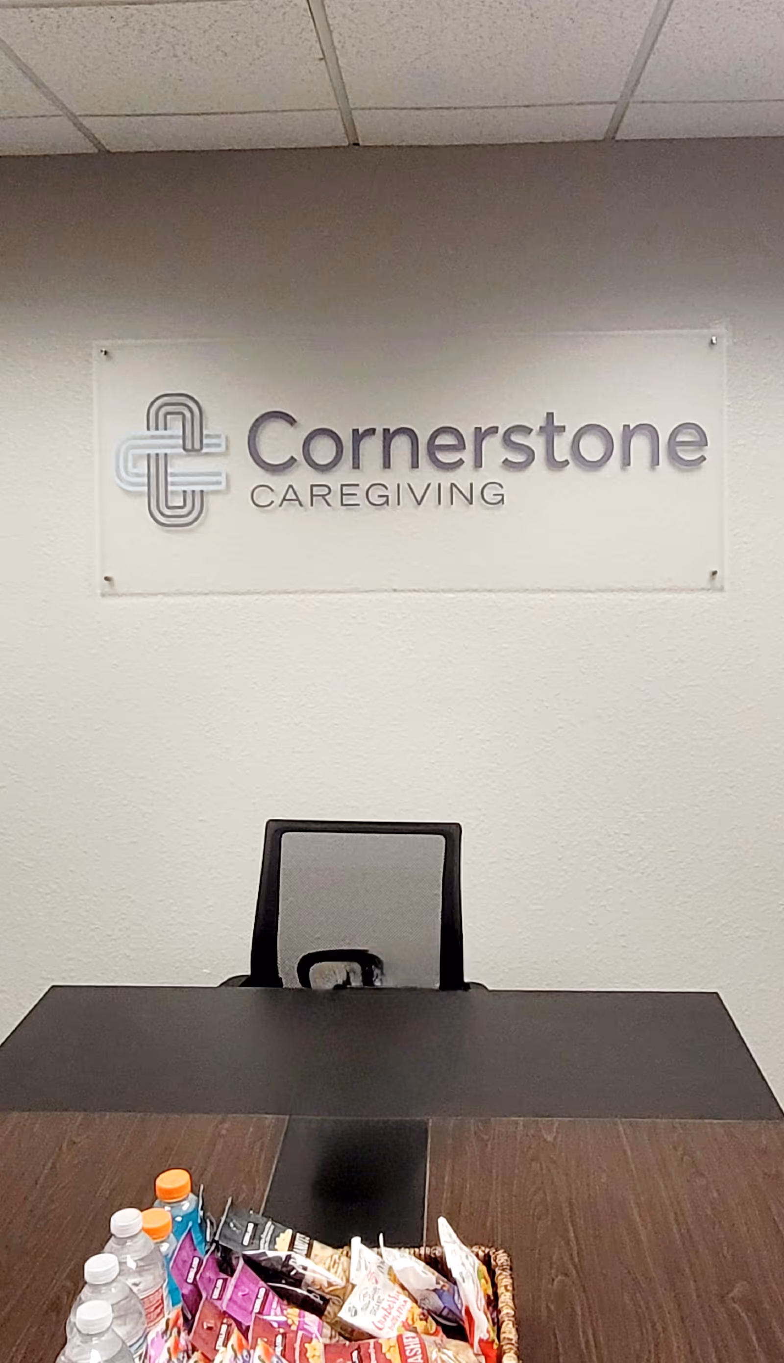 Reception desk in an office with a Cornerstone Caregiving sign on the wall and assorted snacks.