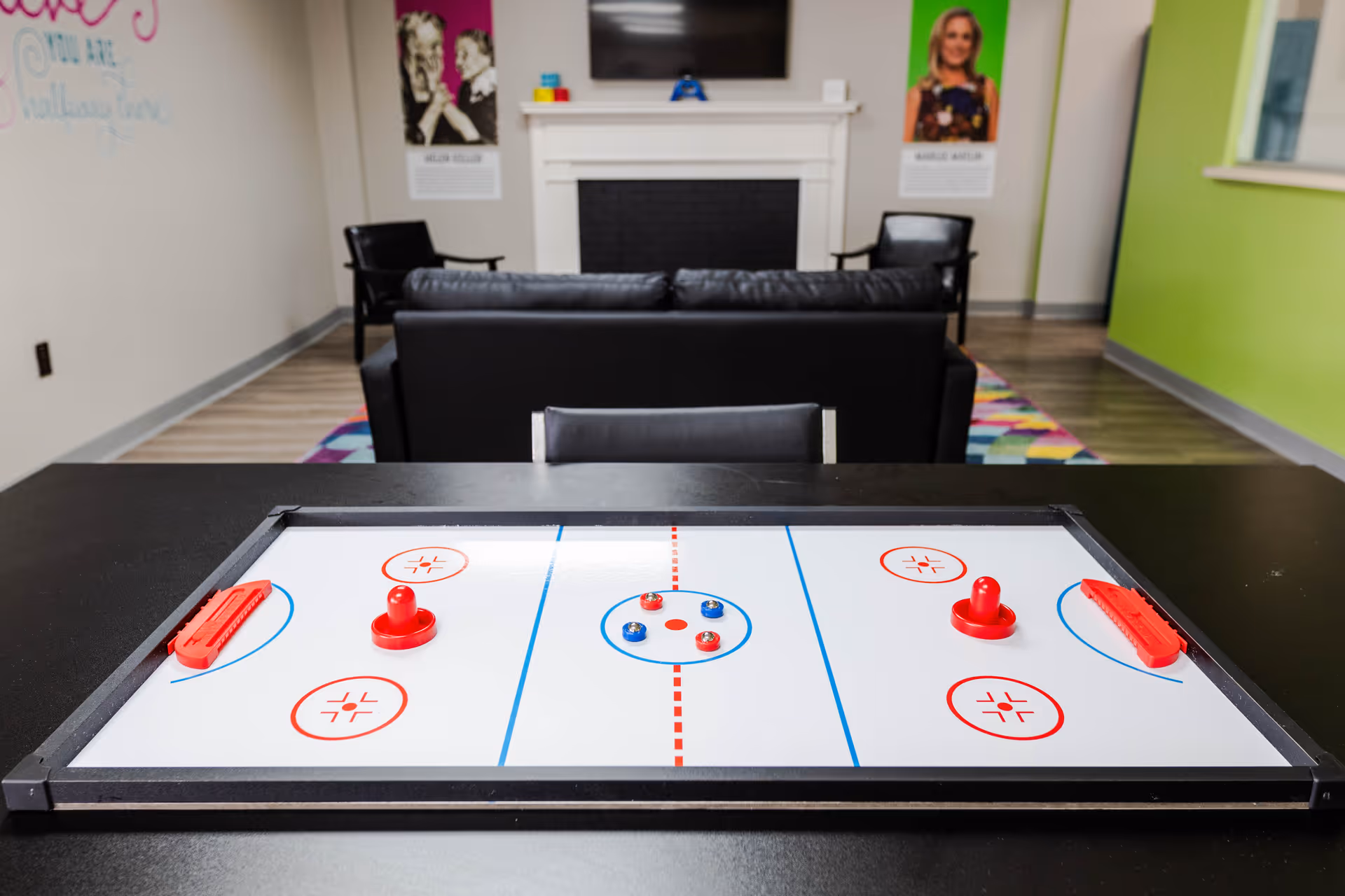 Indoor lounge features a tabletop air hockey game with seating and a fireplace.