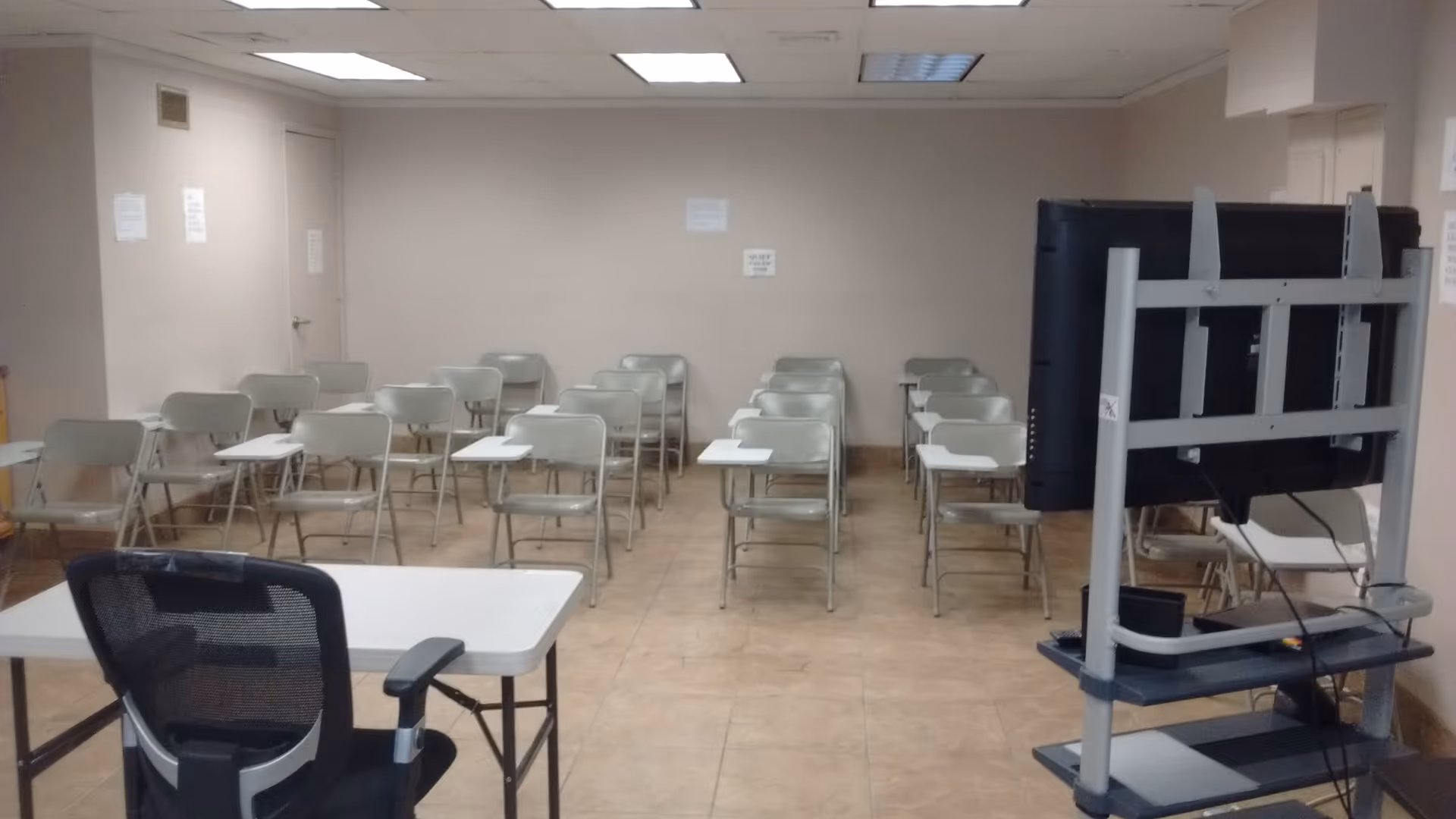 A training room in a senior care facility with folding chairs and a large monitor.