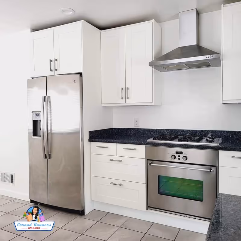 White kitchen with stainless steel appliances and dark countertops.