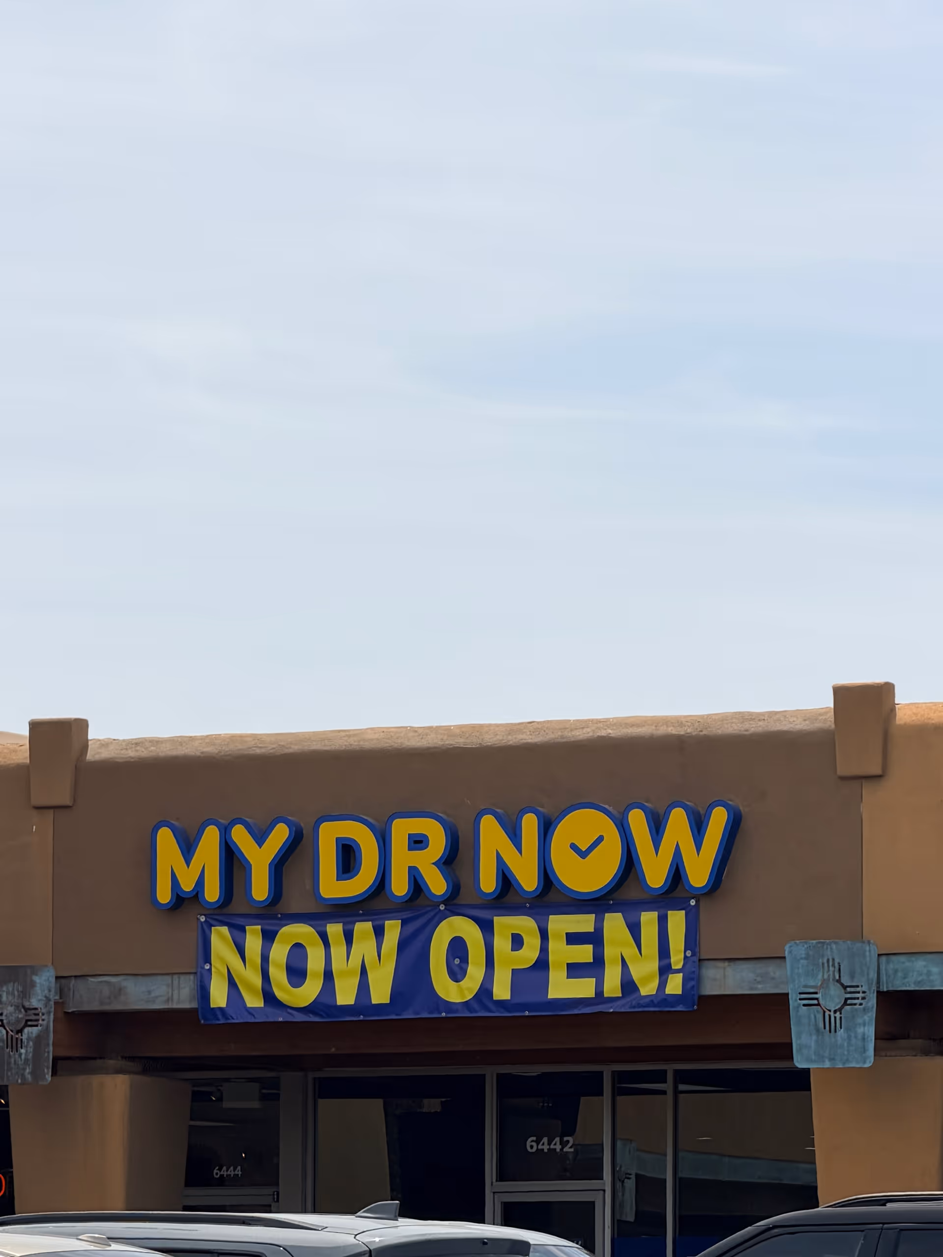 Front of a beige building with a large 'MY DR NOW' sign and 'NOW OPEN' banner.