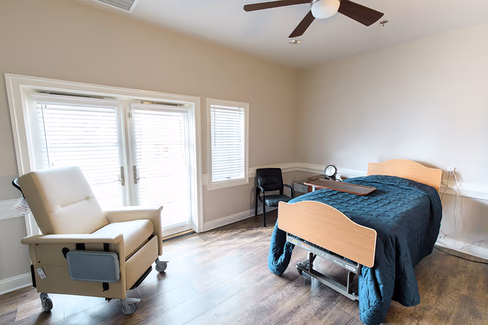 Senior living bedroom with a hospital-style bed, recliner, and ceiling fan.
