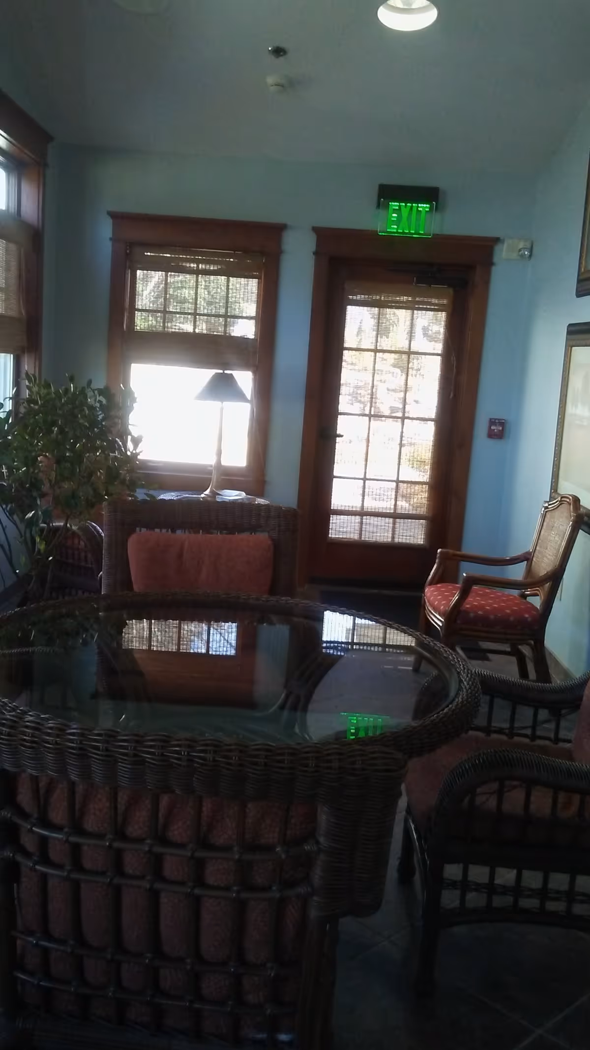 Cozy indoor seating area with a glass-top wicker table and chairs near windows.