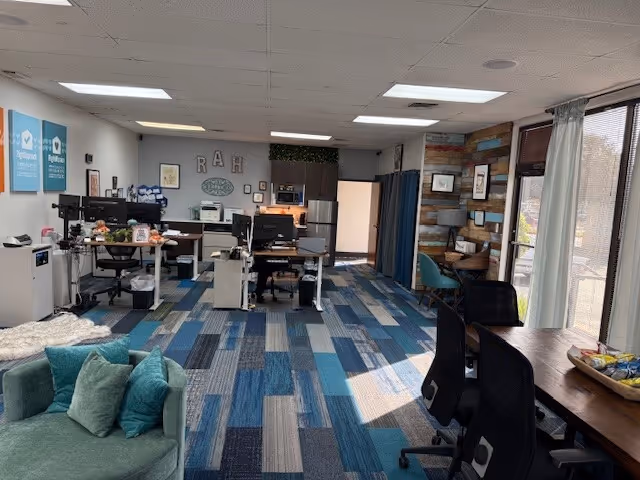 Open area inside Right at Home senior living facility with desks, computers, and teal carpet.