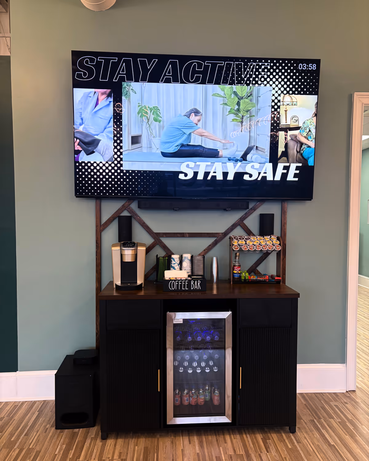 Interior common area with a TV above a coffee bar and beverage fridge.