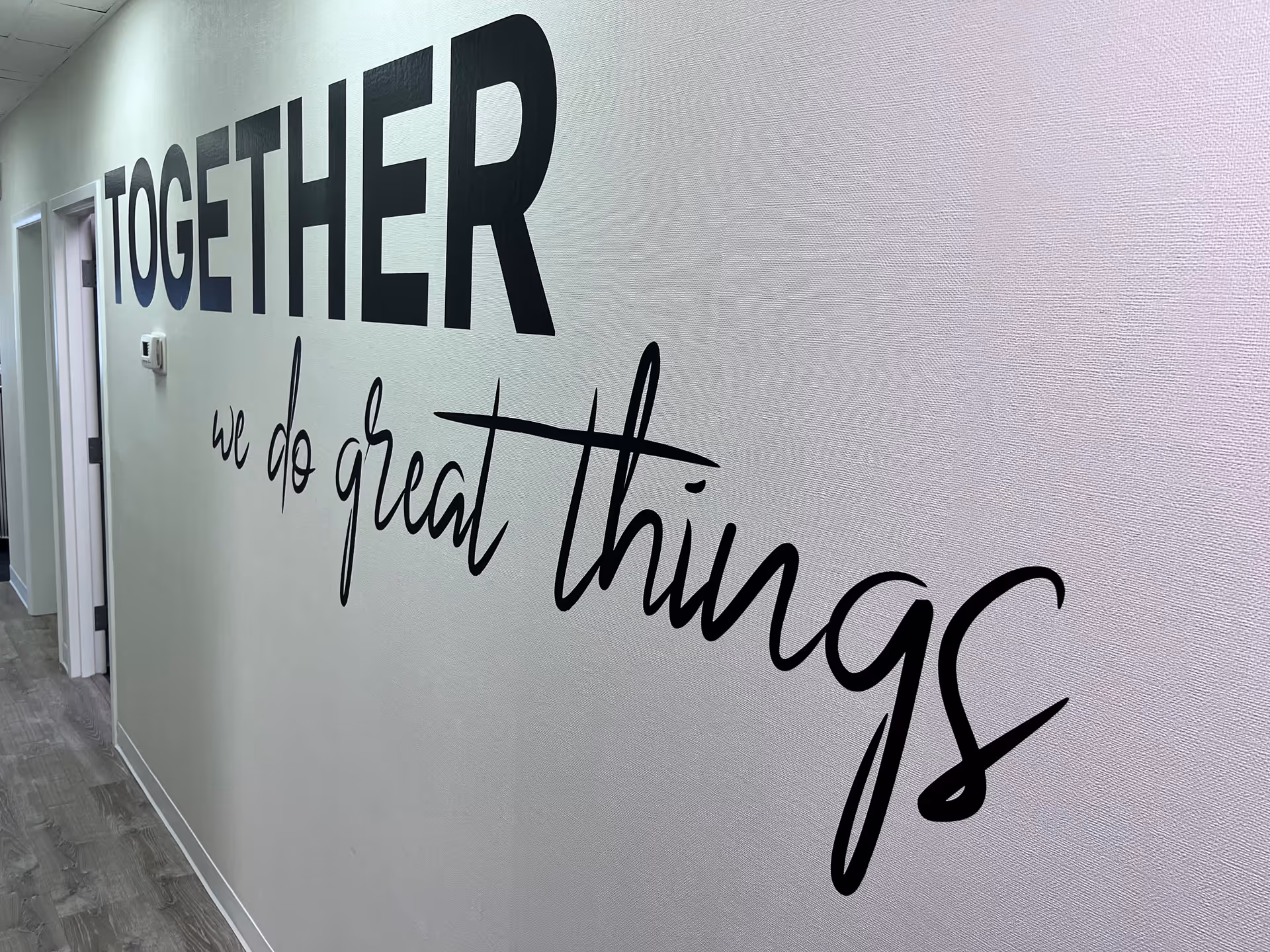 Interior hallway with large wall typography reading 'TOGETHER we do great things'.