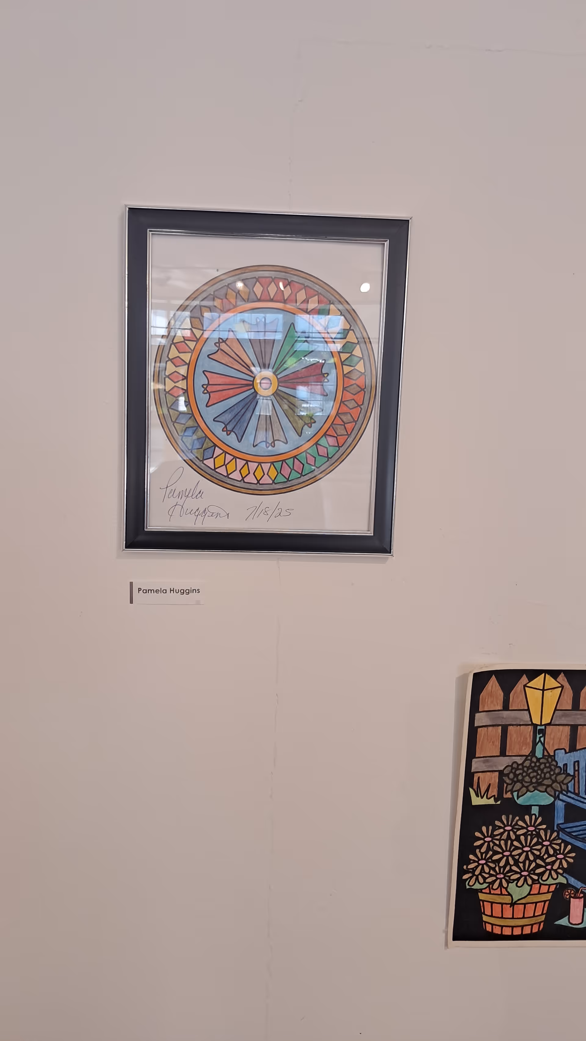 Interior wall with two framed artworks, including a circular color piece and a Pamela Huggins label.