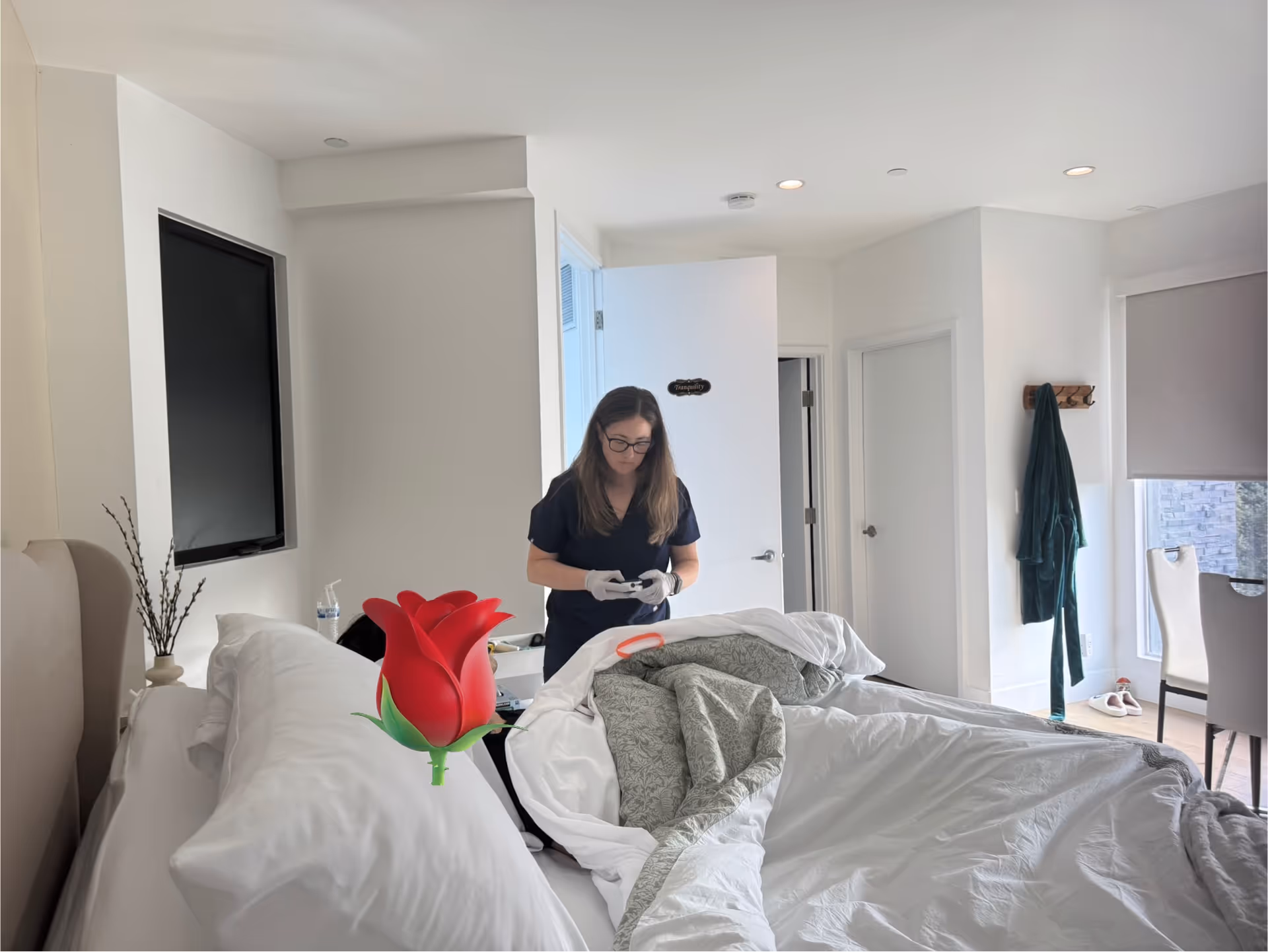Caregiver in scrubs tends to patient on bed in a bright bedroom at Alma Aftercare