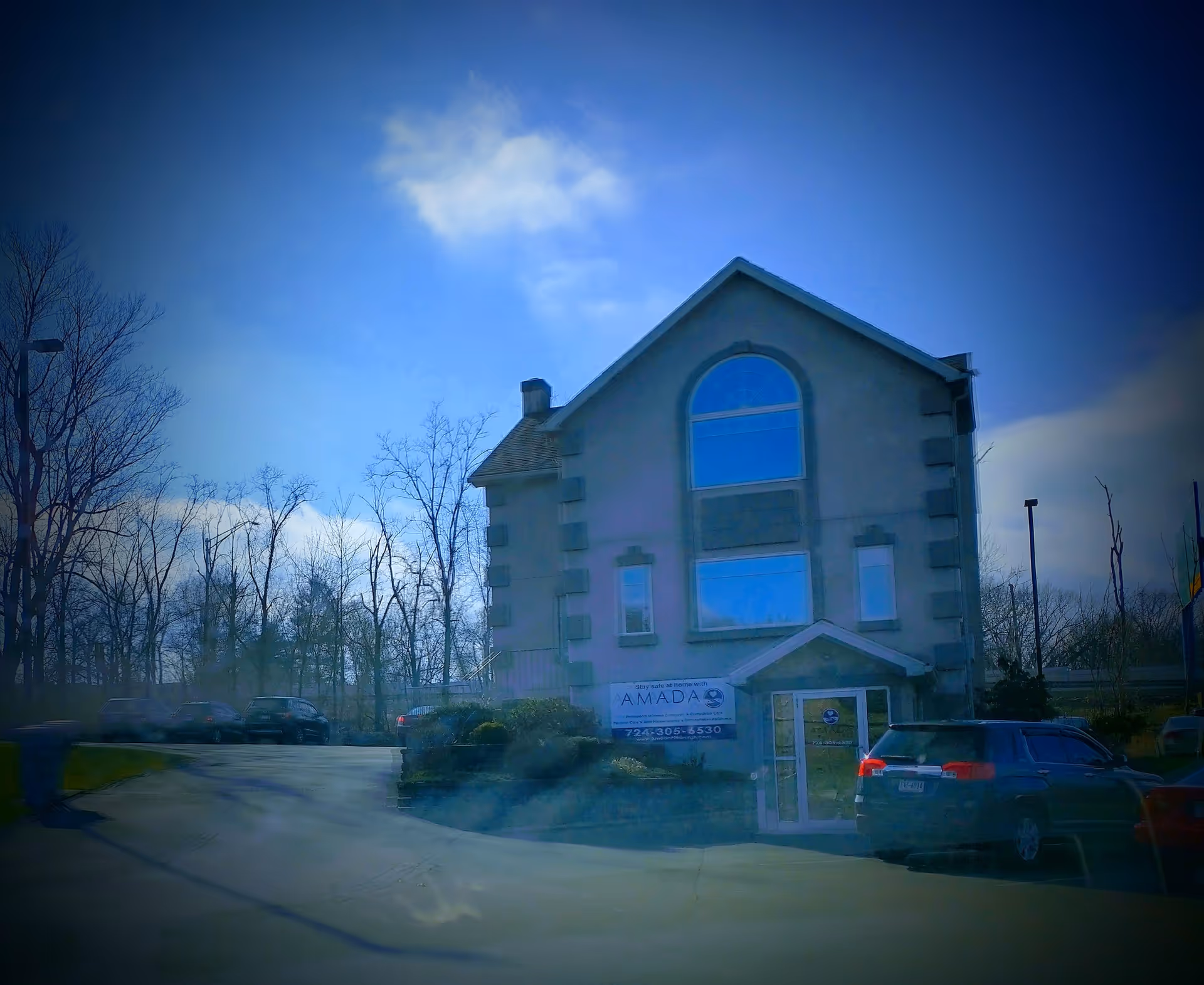 Front view of an Amada Senior Care building with cars in the parking lot.