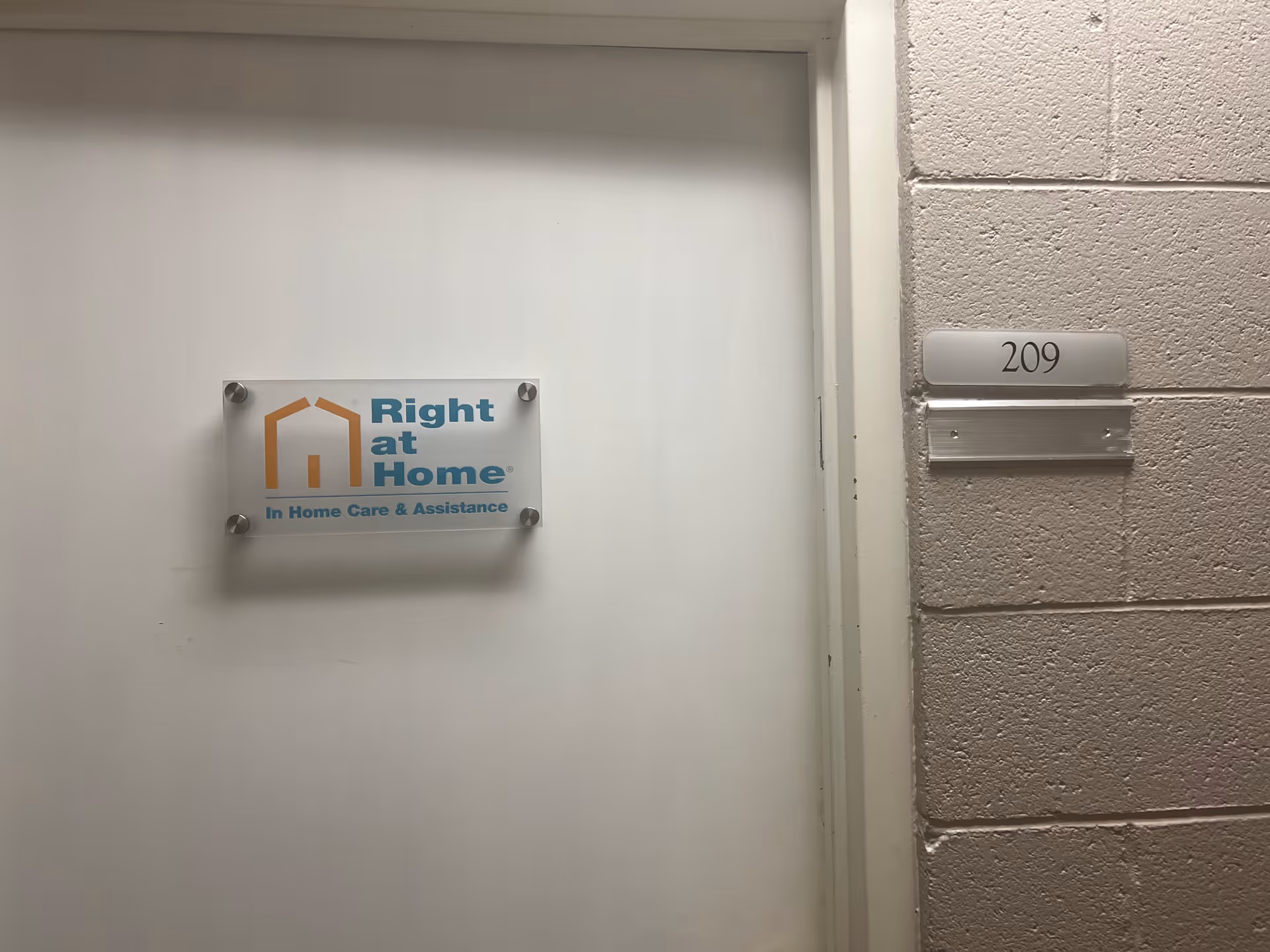 White door with a Right at Home sign and apartment number 209 in a hallway.