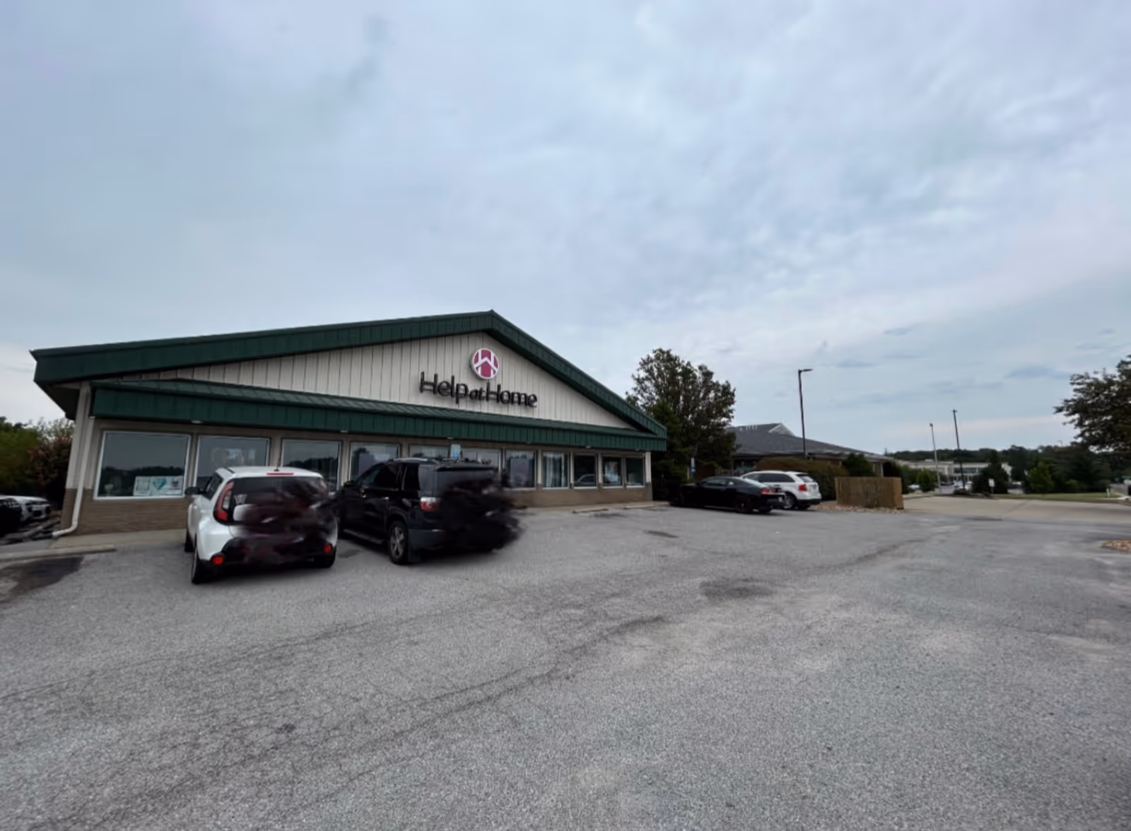 Exterior view of Help at Home facility with cars parked in front.