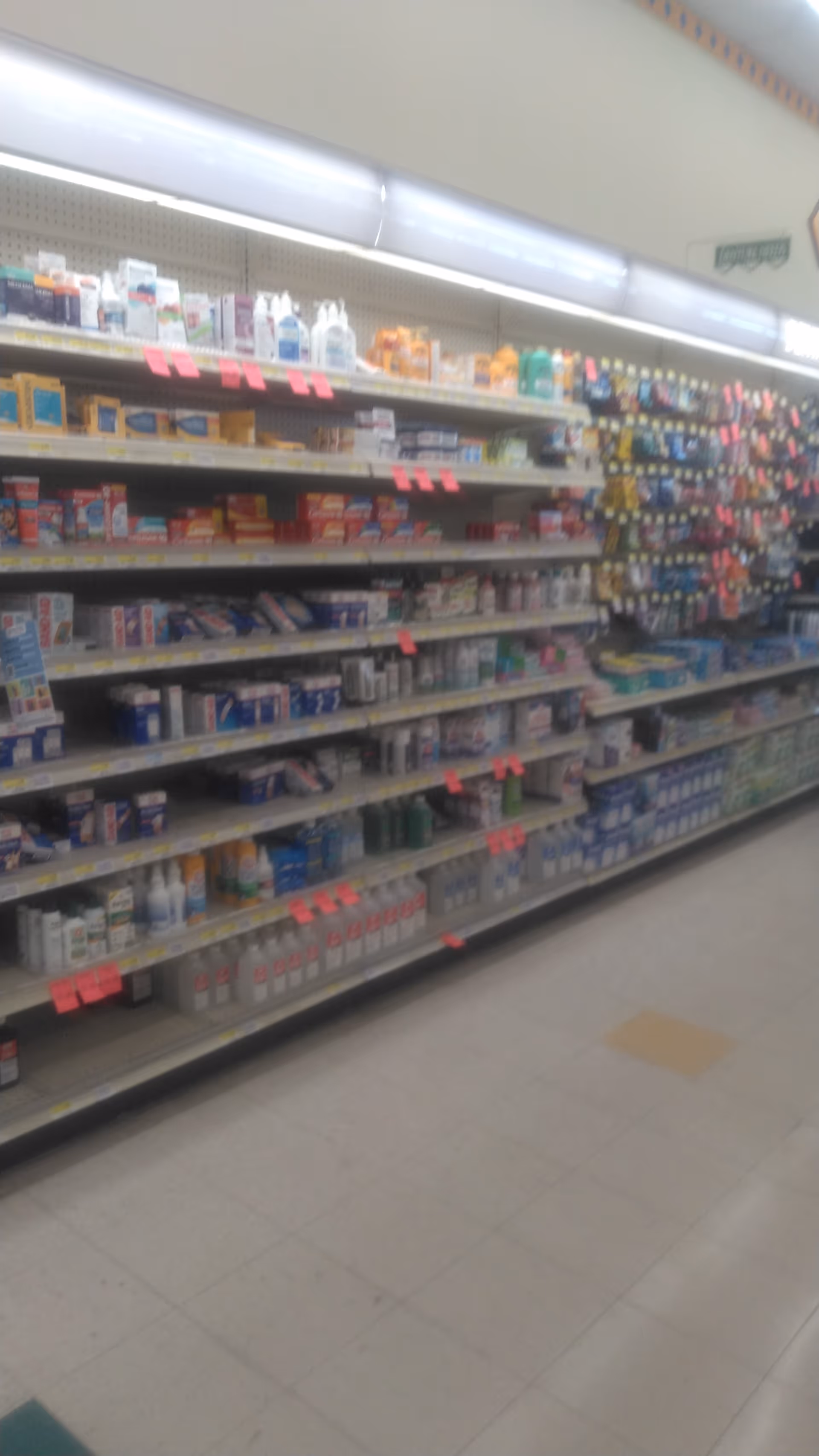 An interior pharmacy aisle with shelves stocked with medicines and health products.