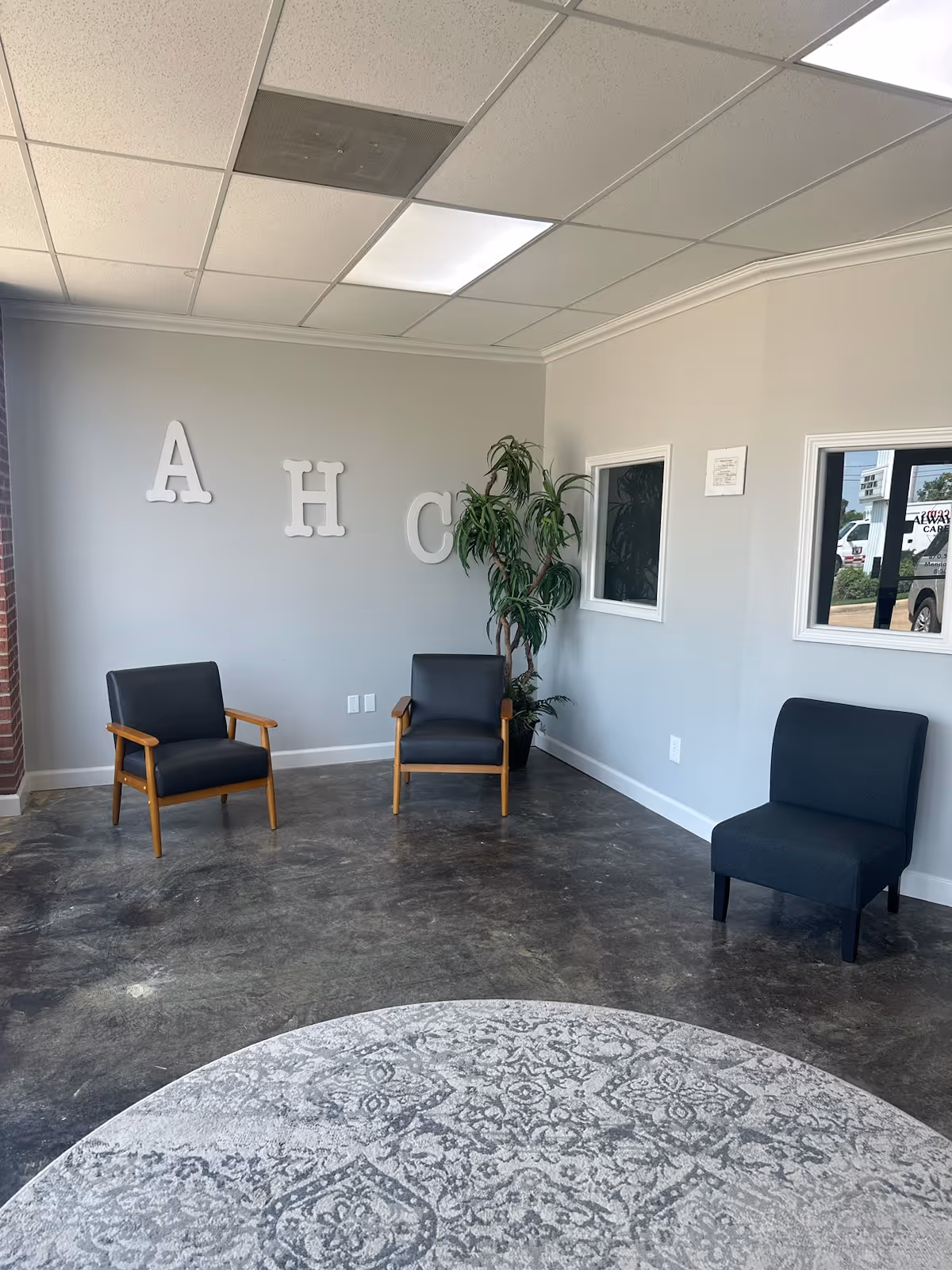 Lobby seating area with four chairs, a plant, and decorative letters on the wall.