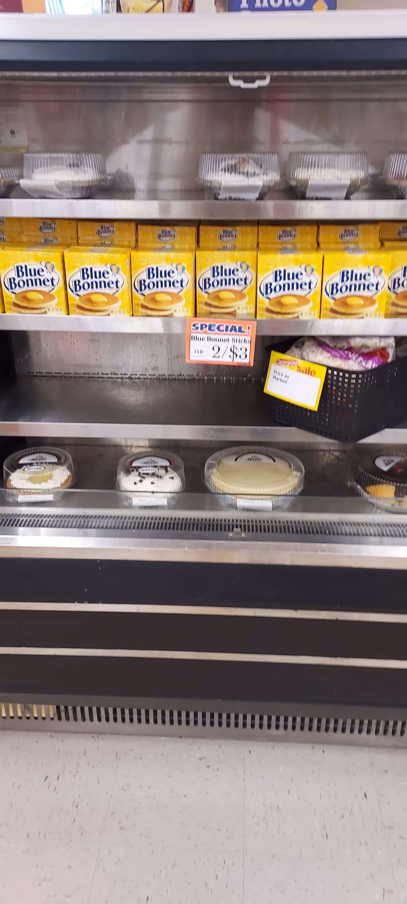 Inside Discount Drug Mart, a refrigerated shelf displays Blue Bonnet margarine and dairy tubs.
