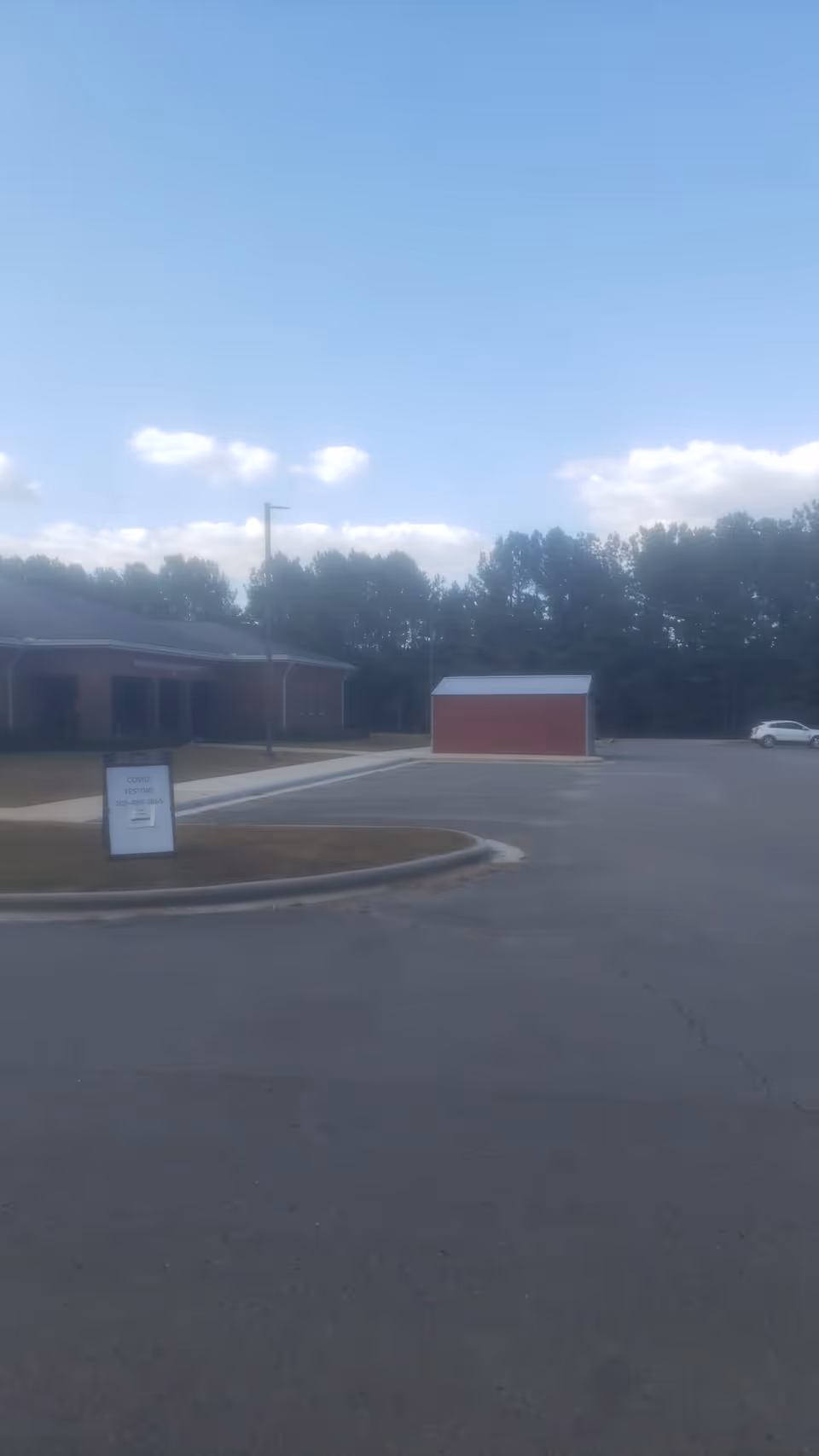 Parking lot with a red shed and brick building under a blue sky