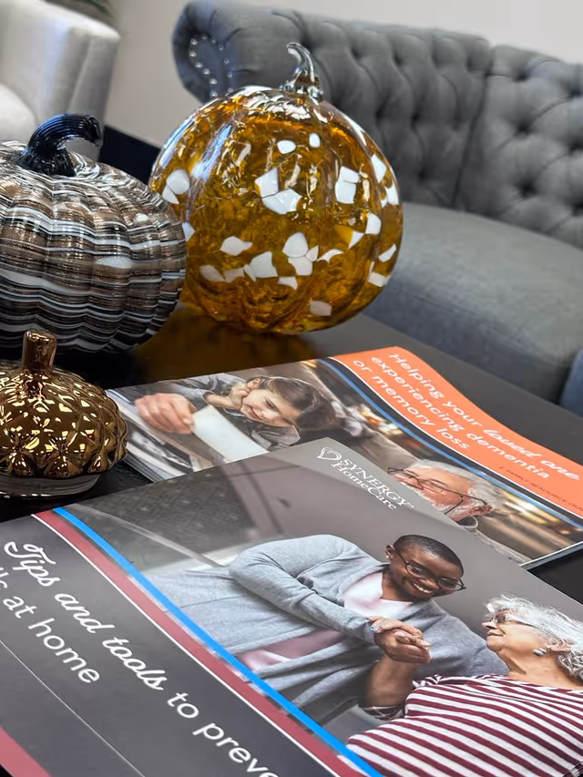 Decorative glass pumpkins sit on a coffee table beside a tufted gray sofa.