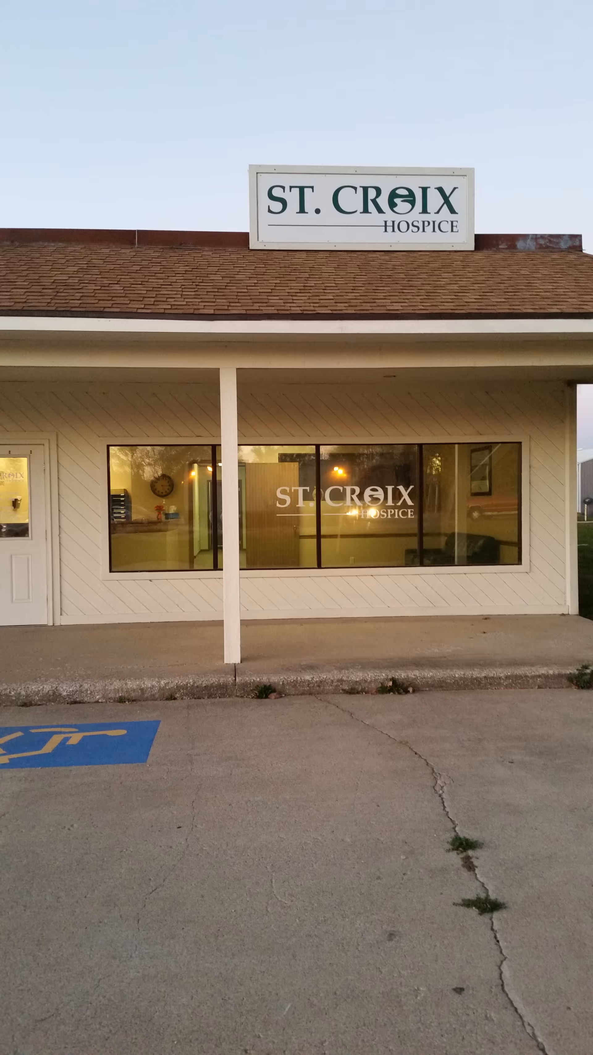 Front exterior of St. Croix Hospice building with sign and entrance windows.