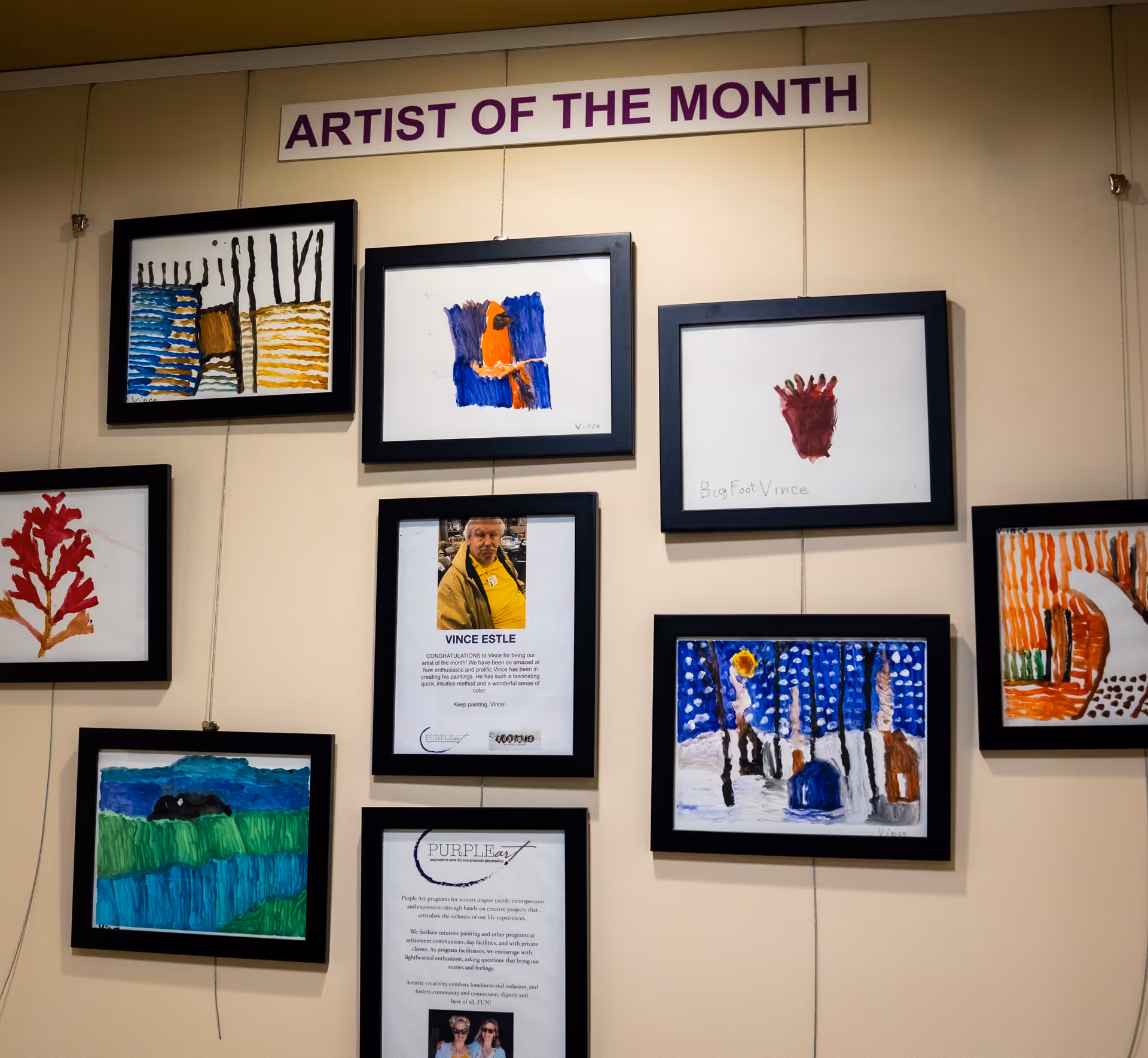 An interior wall displays framed art titled Artist of the Month in a hallway.