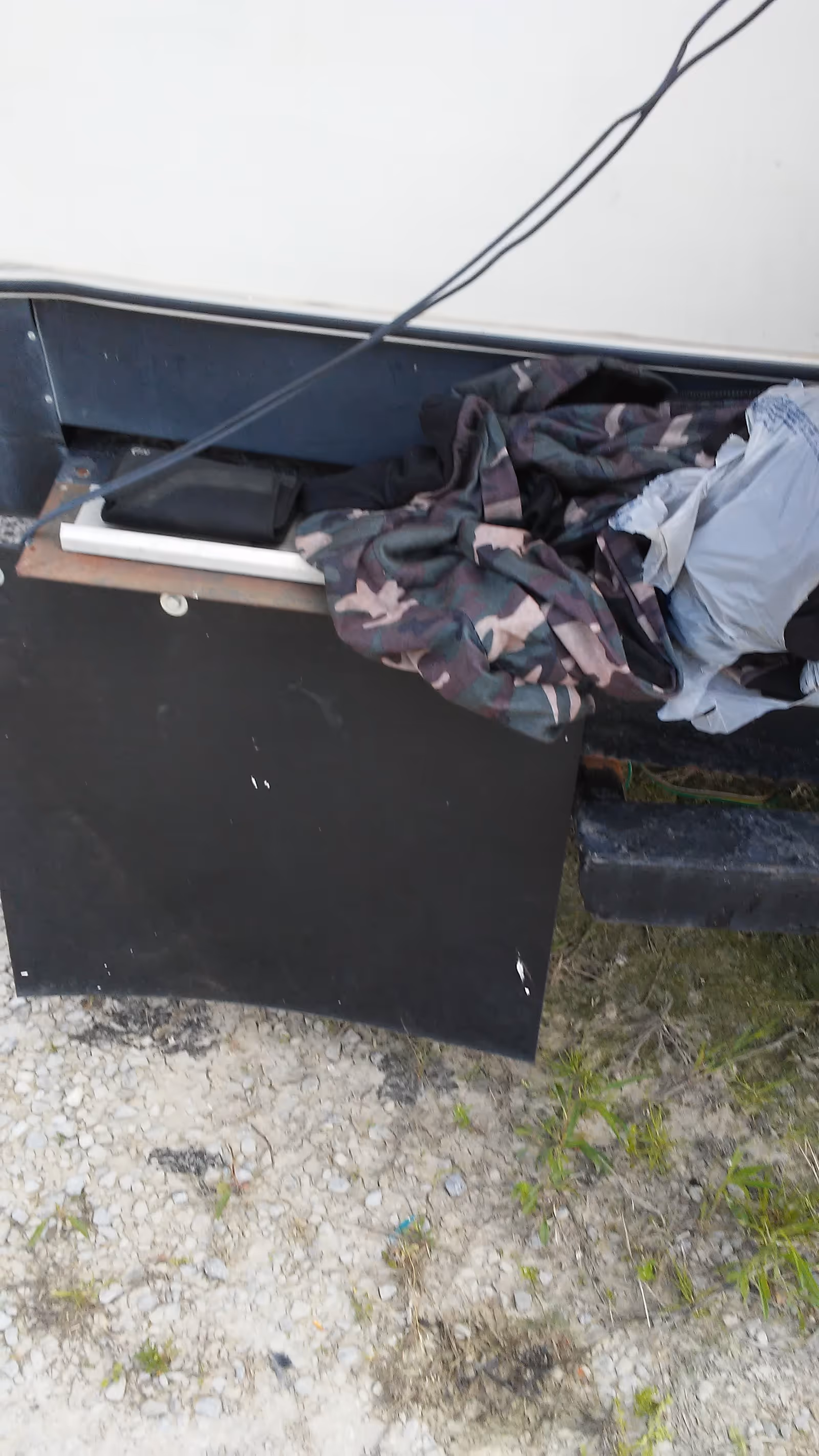 Exterior view of a facility with a black storage cabinet and clothing piled nearby.