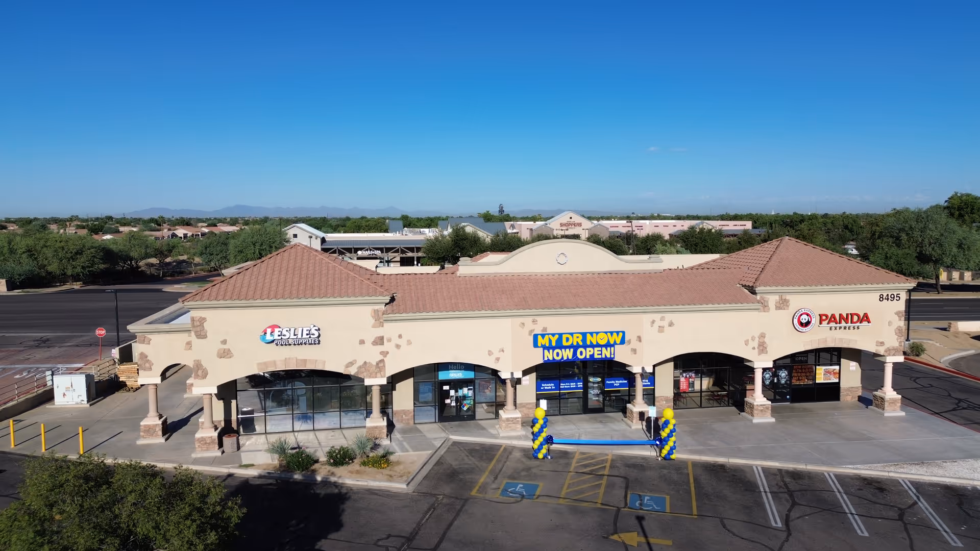 Exterior view of a strip mall with a My Dr Now clinic and parking.
