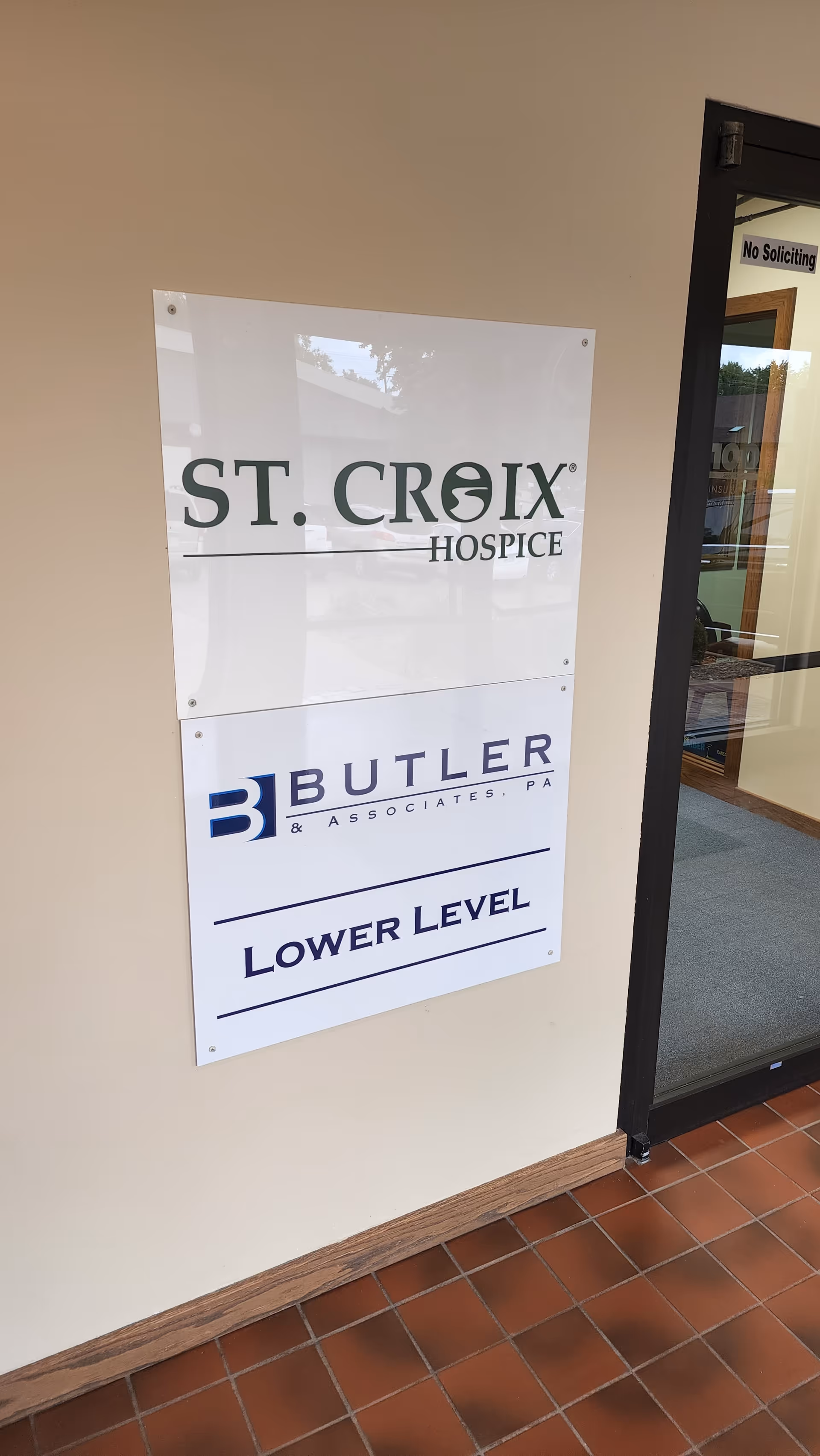 Interior wall sign for St. Croix Hospice with Butler Associates Lower Level beside a glass door.