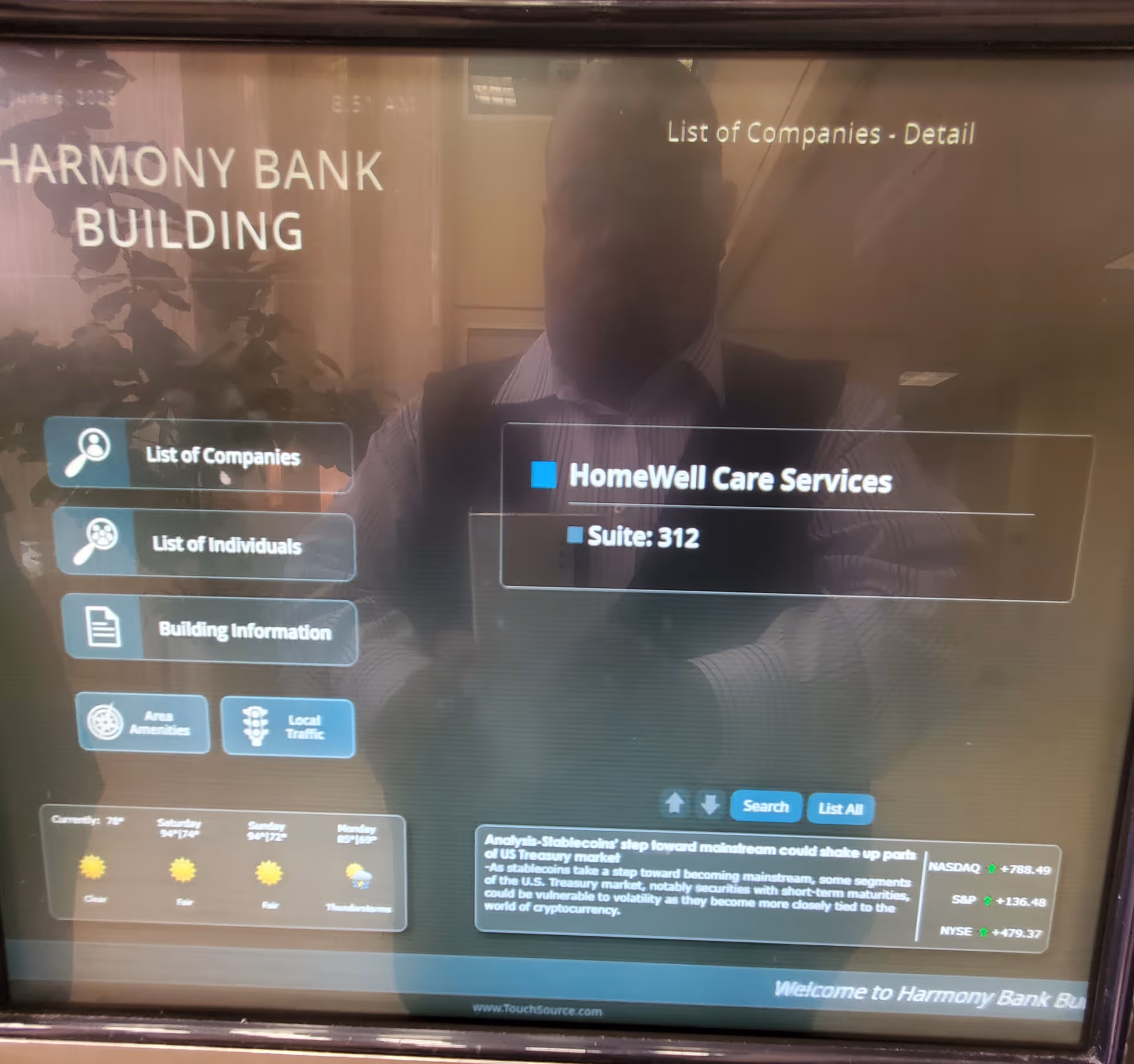 Reflection on a bank directory screen showing HomeWell Care Services in Harmony Bank Building