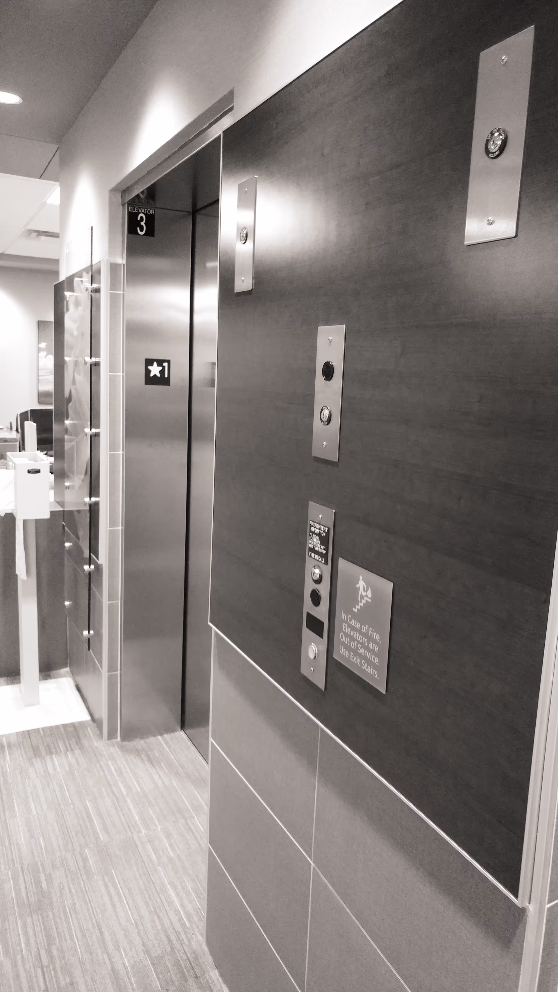Interior hallway with an elevator door and dark wood paneling along the corridor.