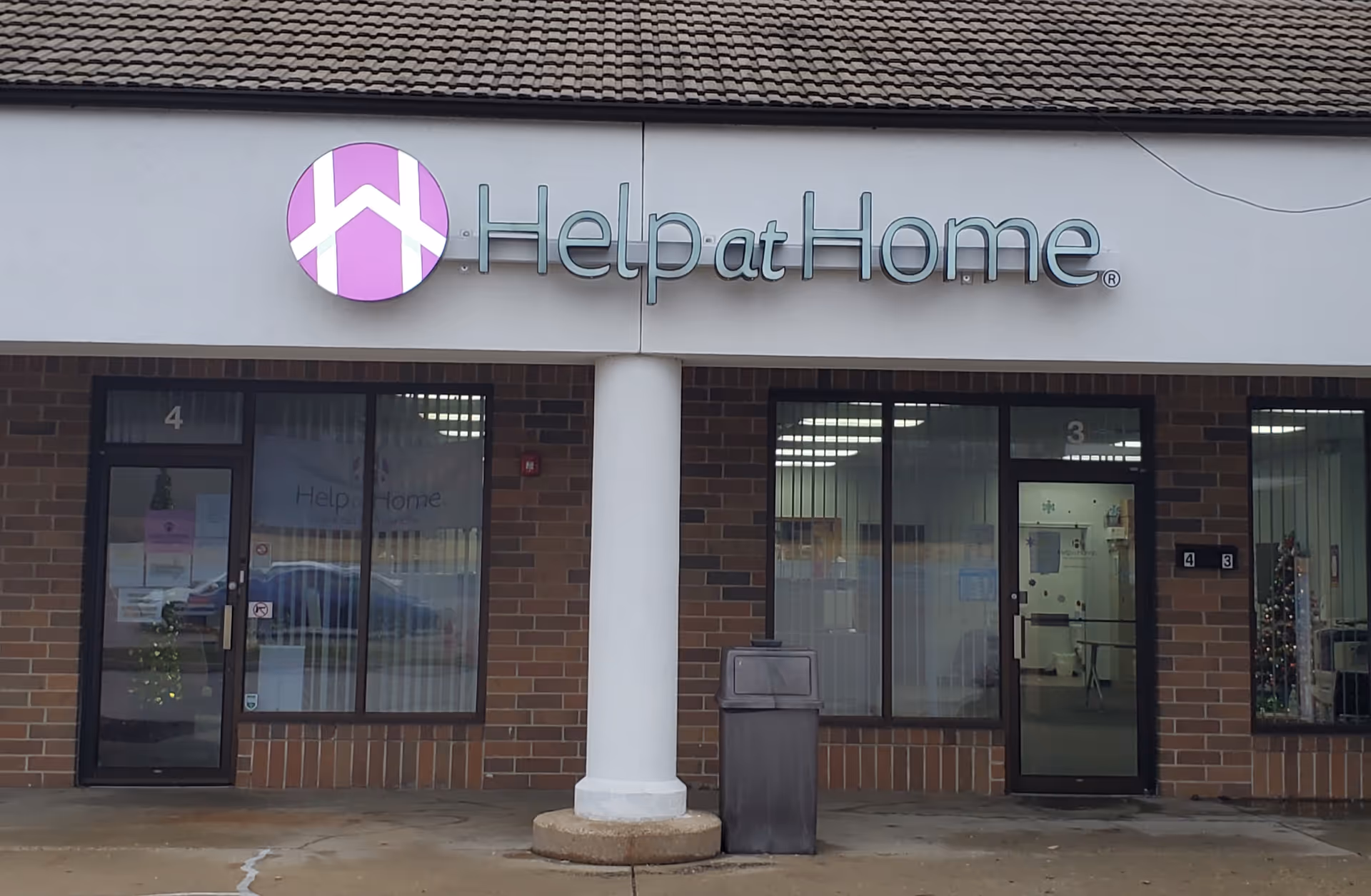 Exterior of a Help at Home facility with glass doors, sign, and a white column.