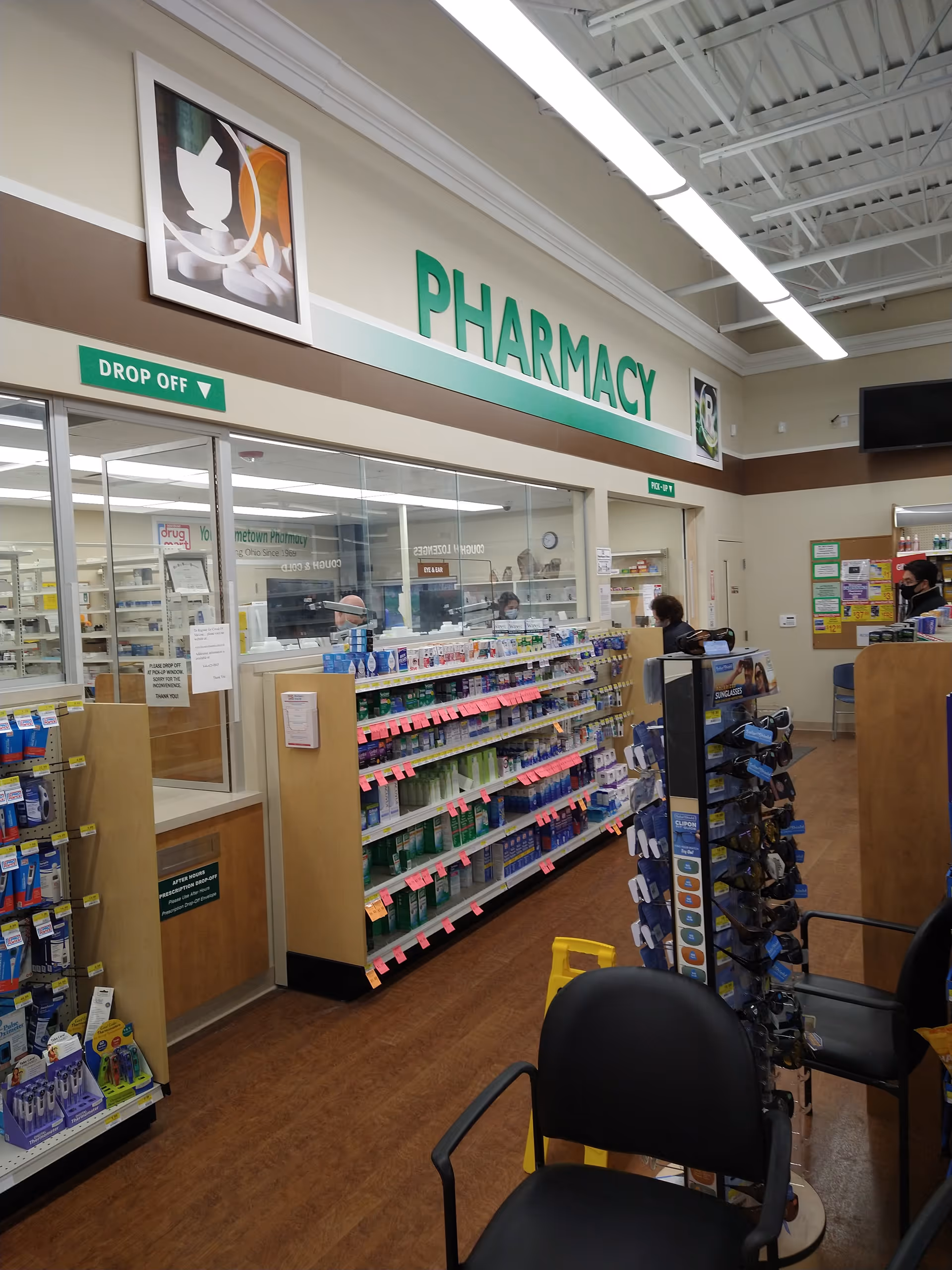 Inside a Discount Drug Mart pharmacy with shelves, signage, and a checkout area.