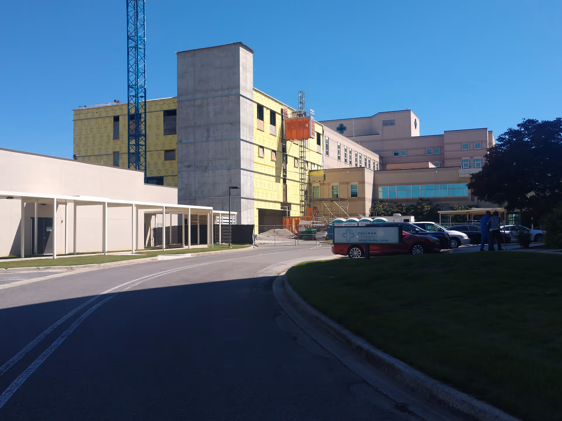 Exterior view of a medical center under construction with cranes and vehicles