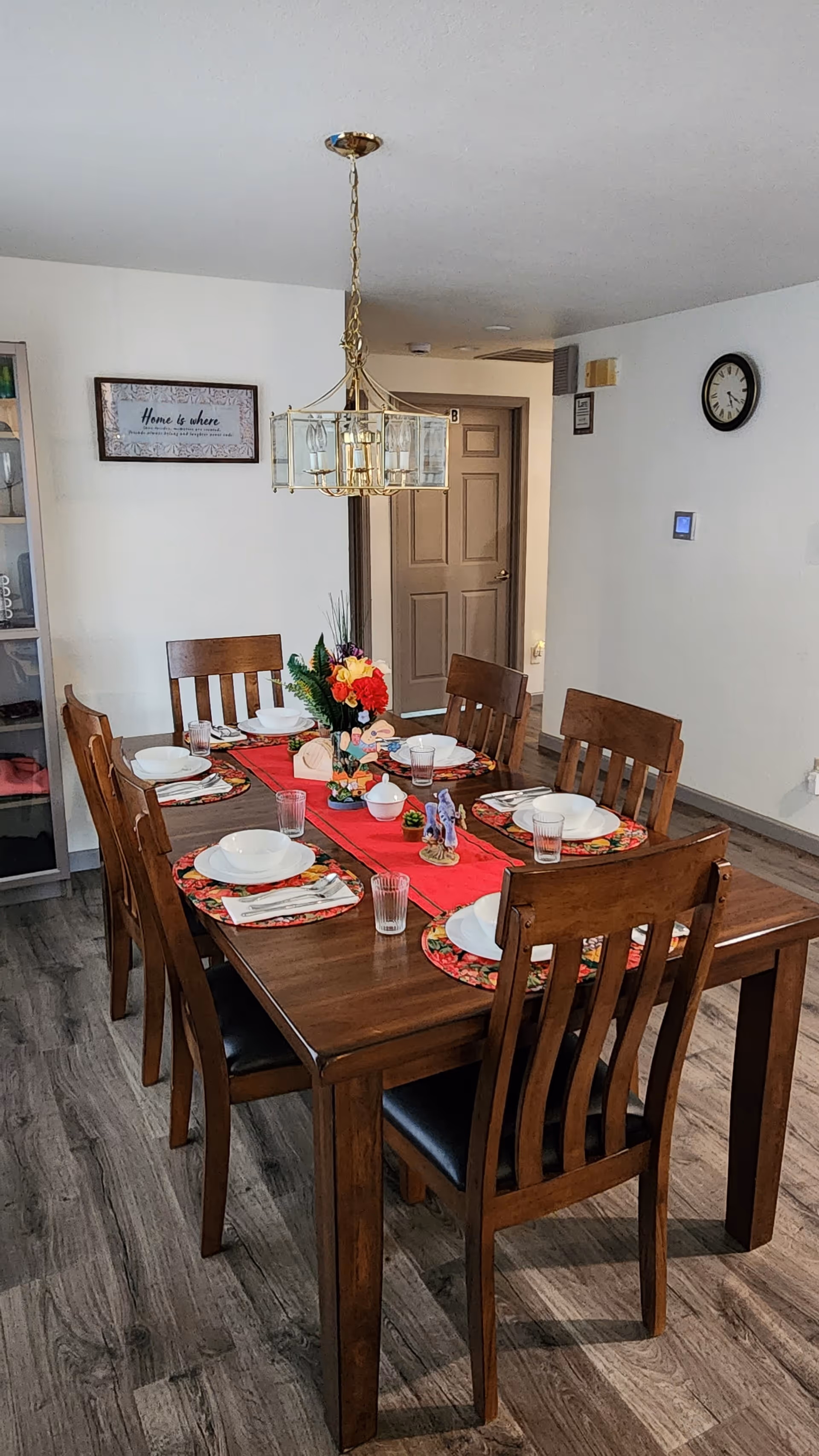 Wooden dining table set for eight with centerpiece in a senior living dining room.