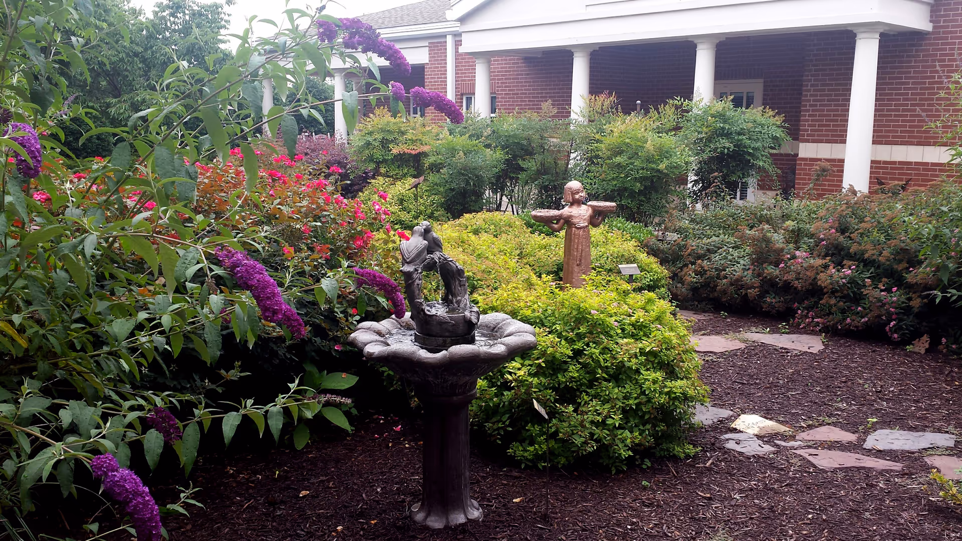 Outdoor garden courtyard of Circle of Life facility with fountain and blooming shrubs.