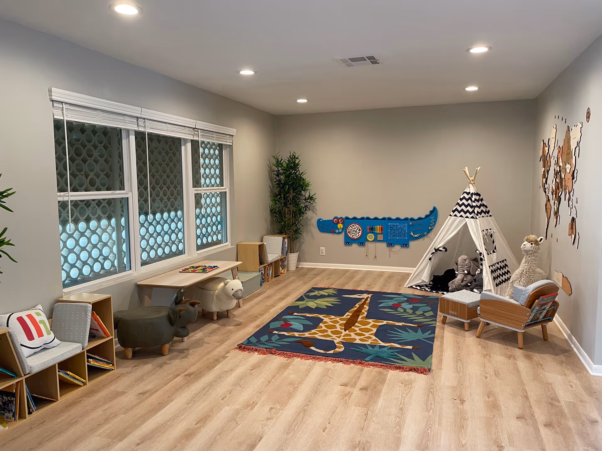 Bright children's activity room with a teepee tent, rug, shelves, and toys.