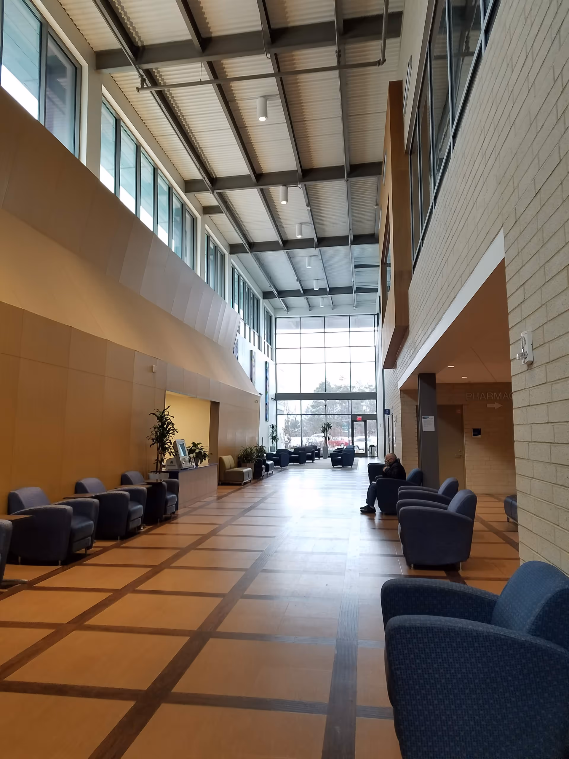 Bright hospital-style lobby with high ceilings, large windows, and blue chairs along the seating area.