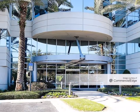 Entrance to Amada Senior Care facility with glass doors and palm trees.