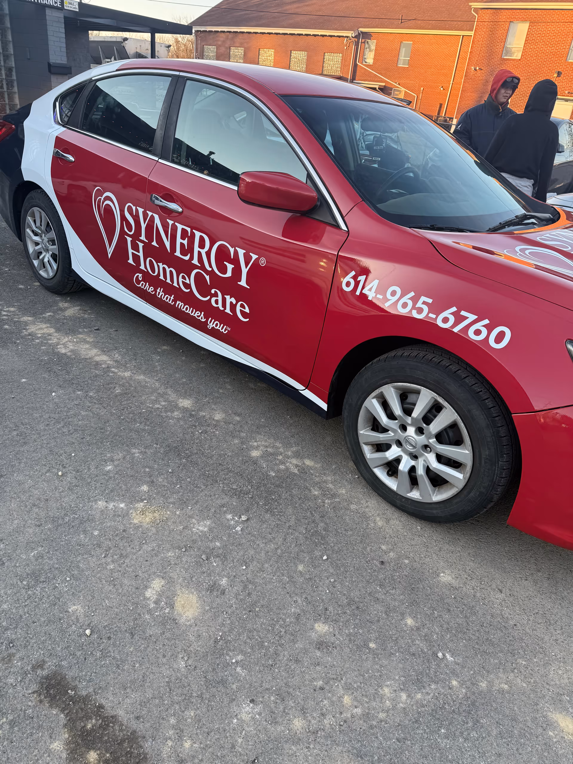 A SYNERGY HomeCare branded car parked in an outdoor lot.