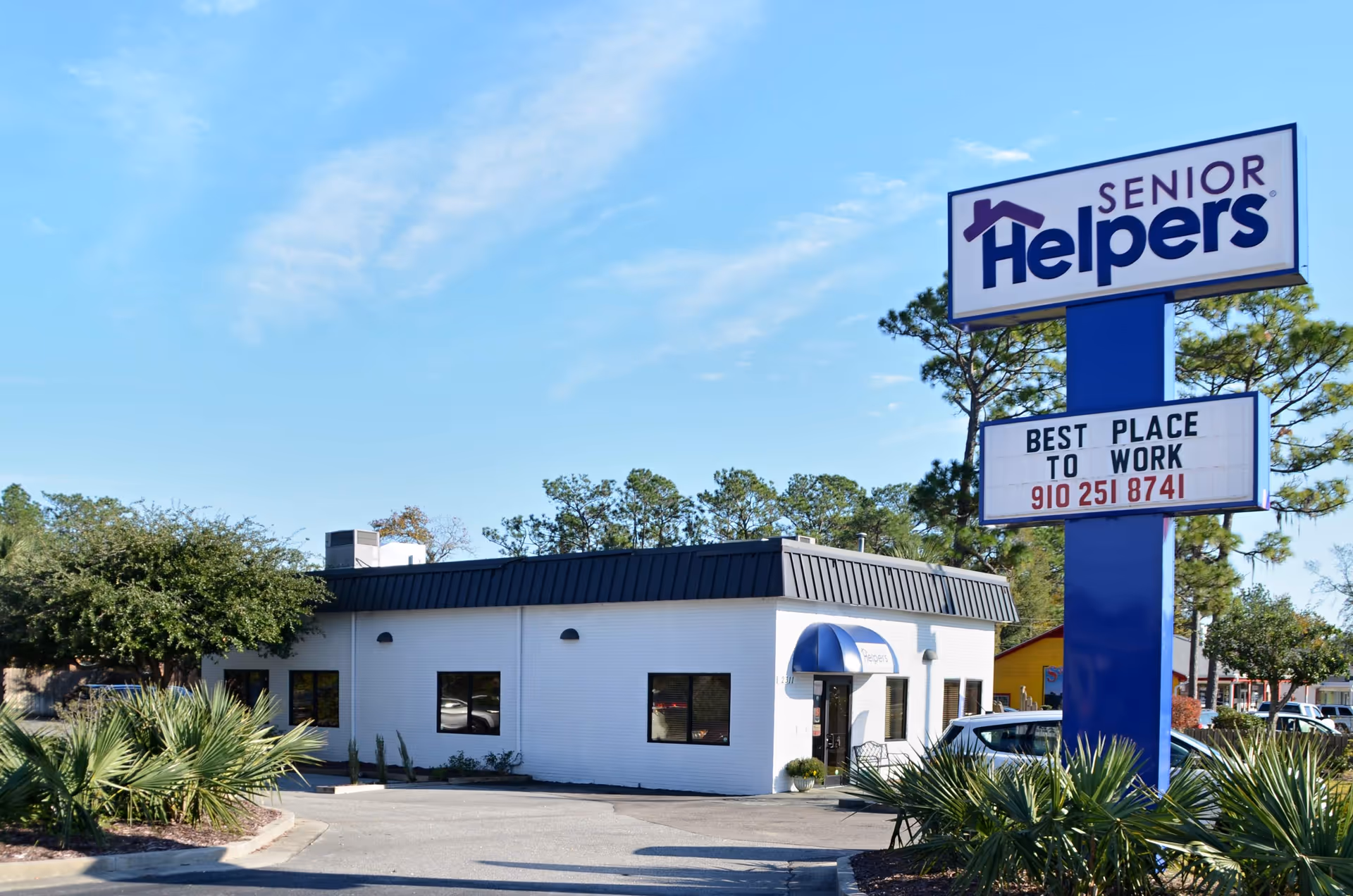 Exterior view of a Senior Helpers facility with a large blue sign and white building