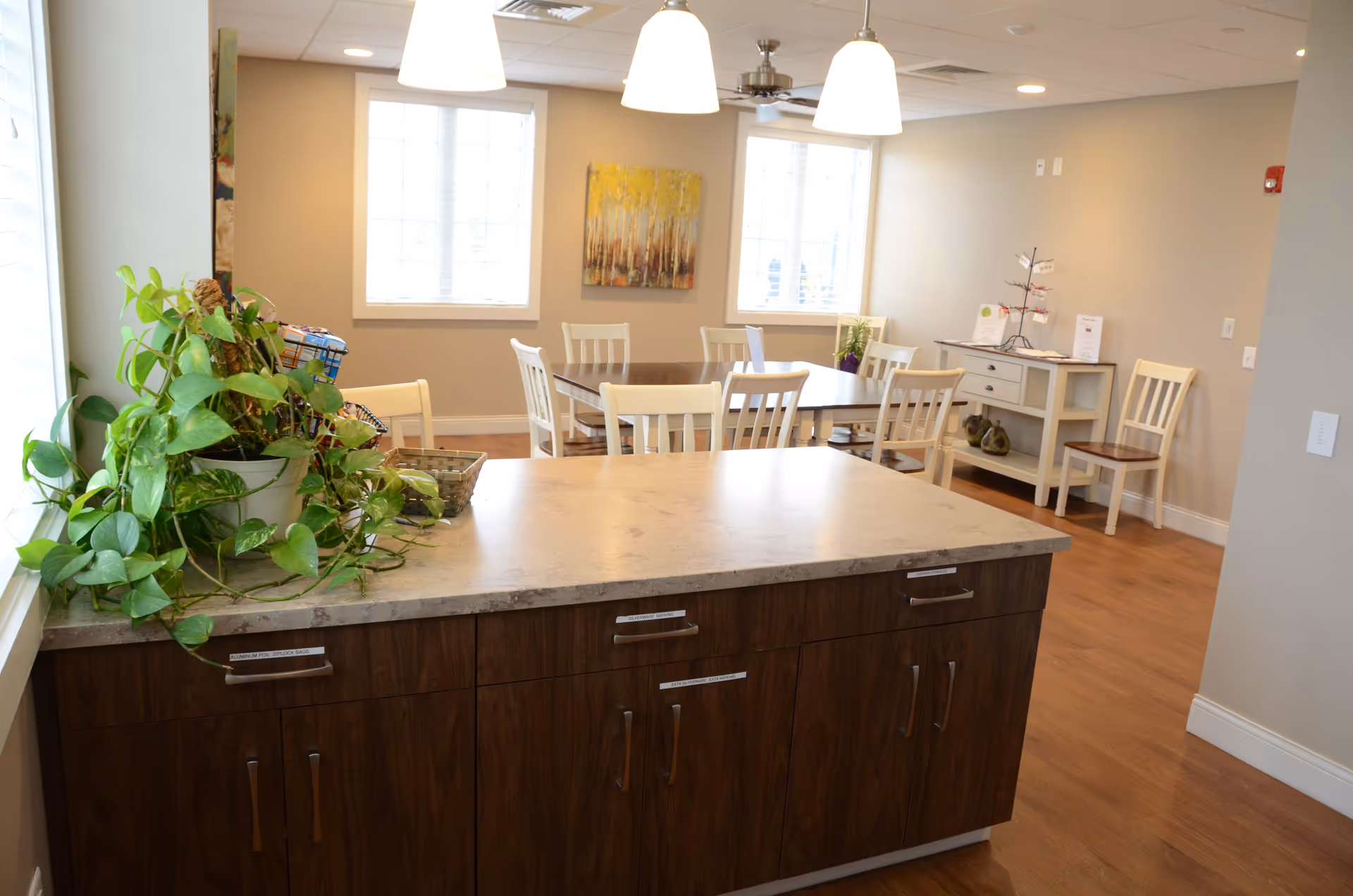 Interior common area with a kitchen island, wood cabinetry, and dining tables.