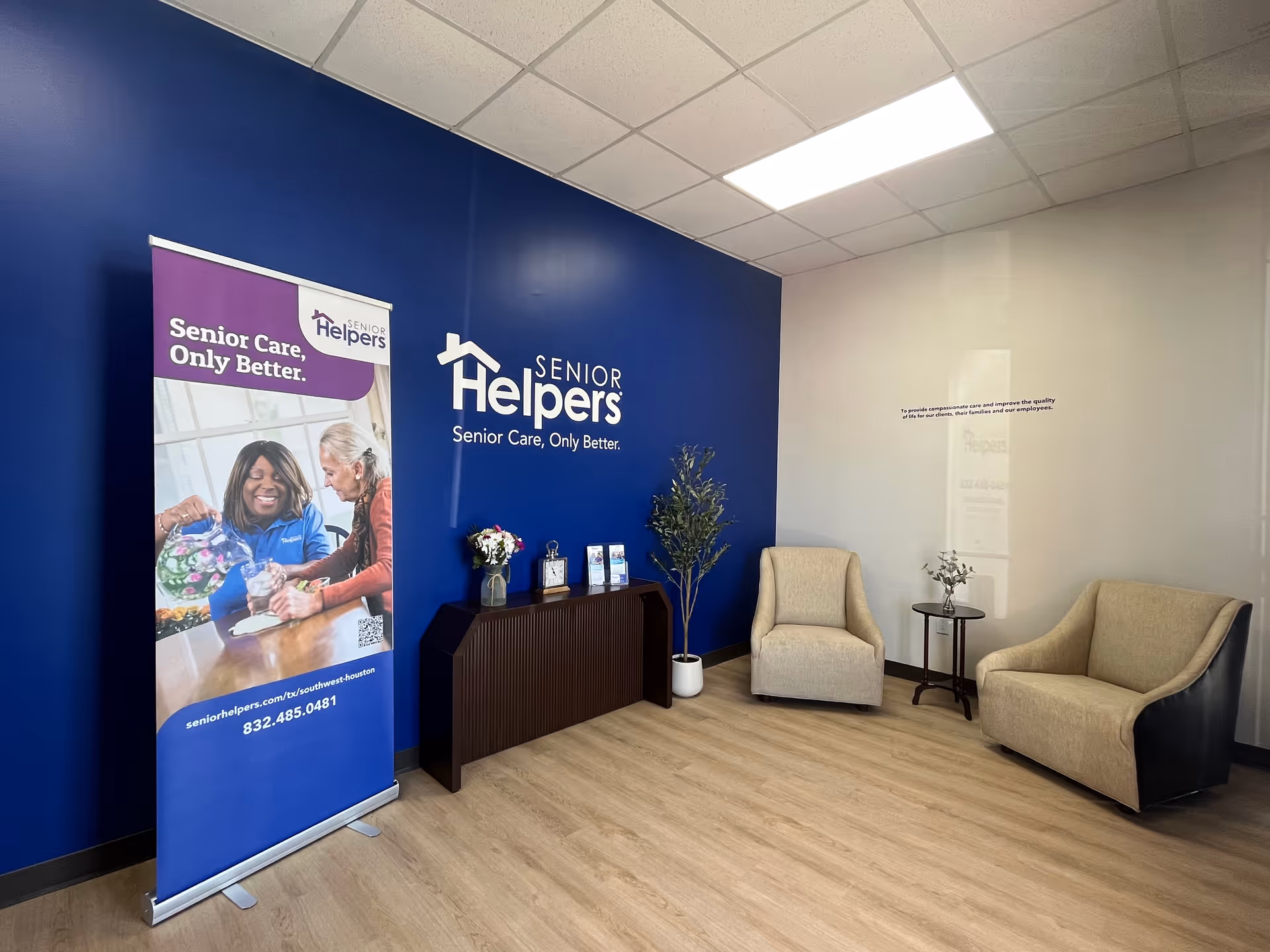 Modern lobby with blue wall, Senior Helpers logo, and beige seating area.