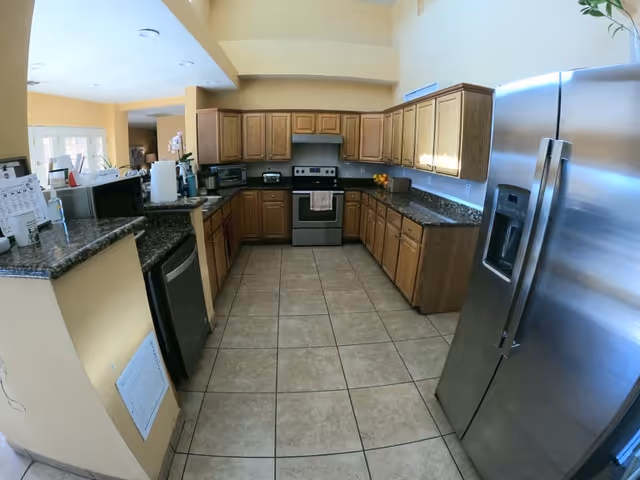 Spacious U-shaped kitchen with wooden cabinets, granite countertops, and stainless steel appliances.