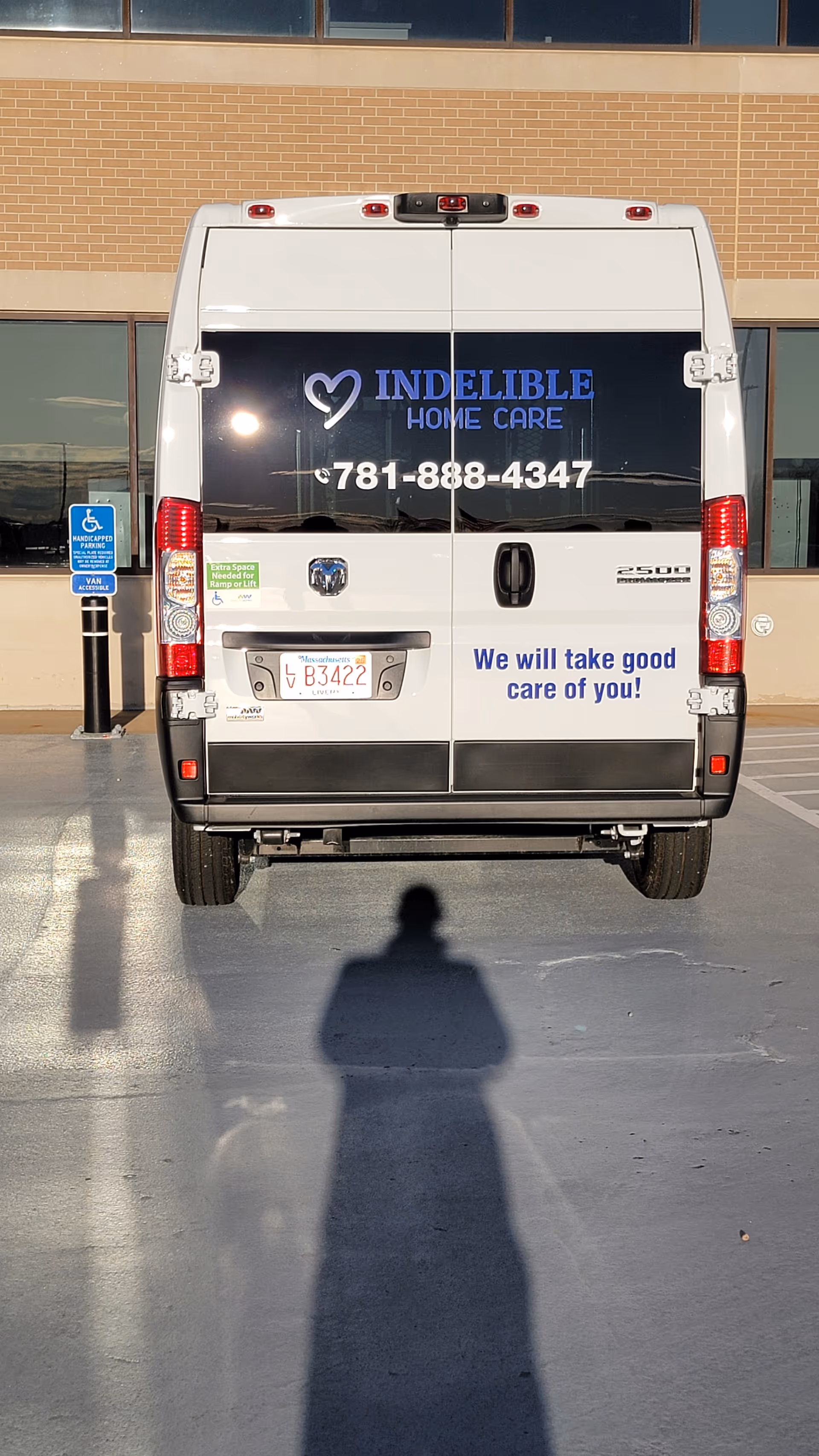 Back of a white Indelible Home Care van parked in a lot by a brick building.