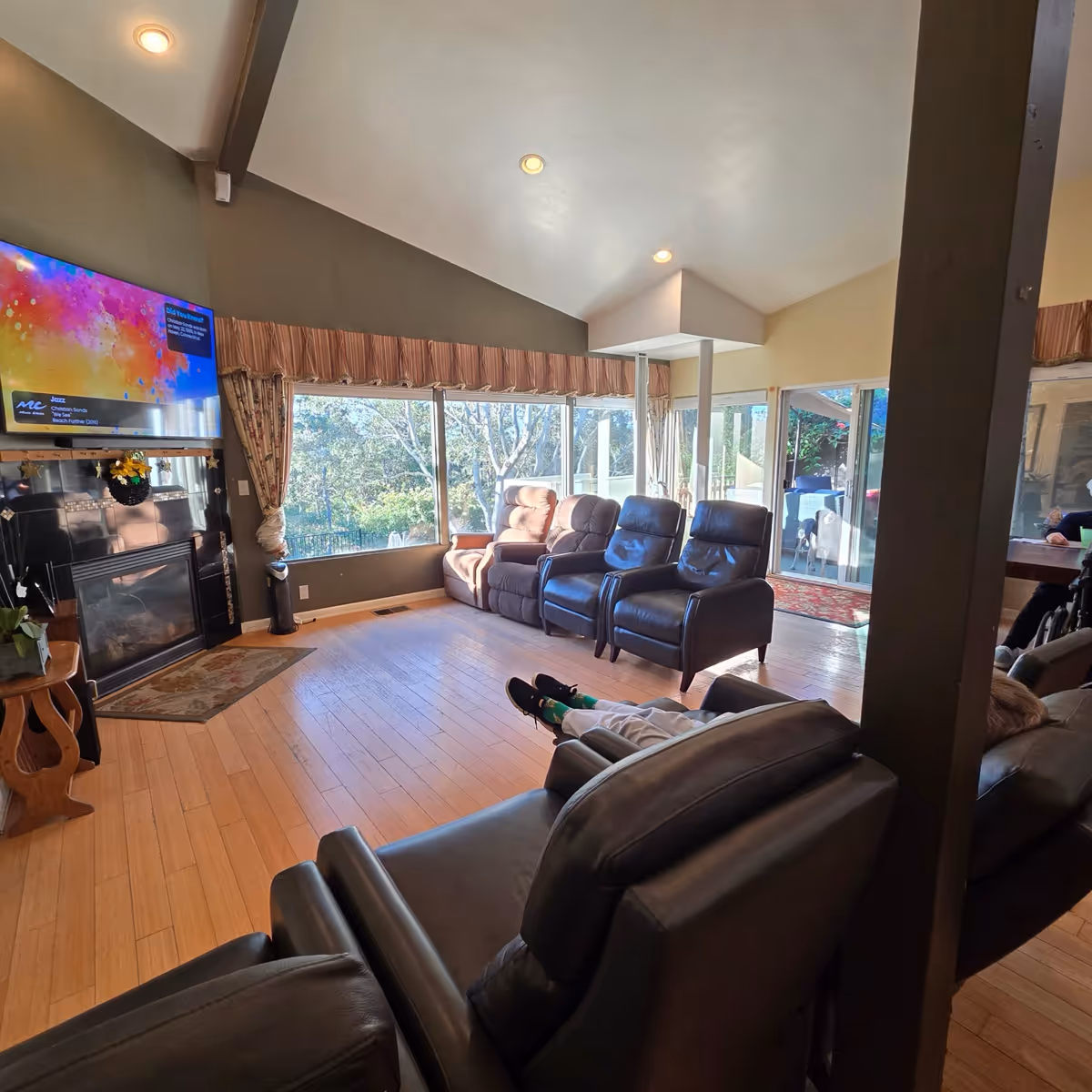 A spacious living room with leather recliners, a fireplace, and a wall-mounted TV.