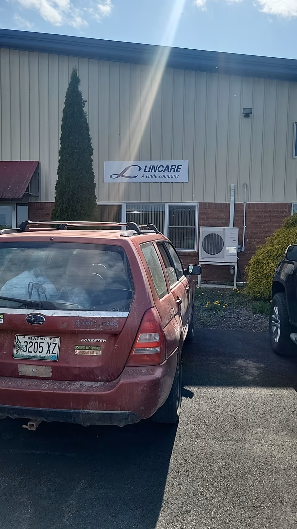 Exterior view of a LINCARE building with parked cars in the foreground.