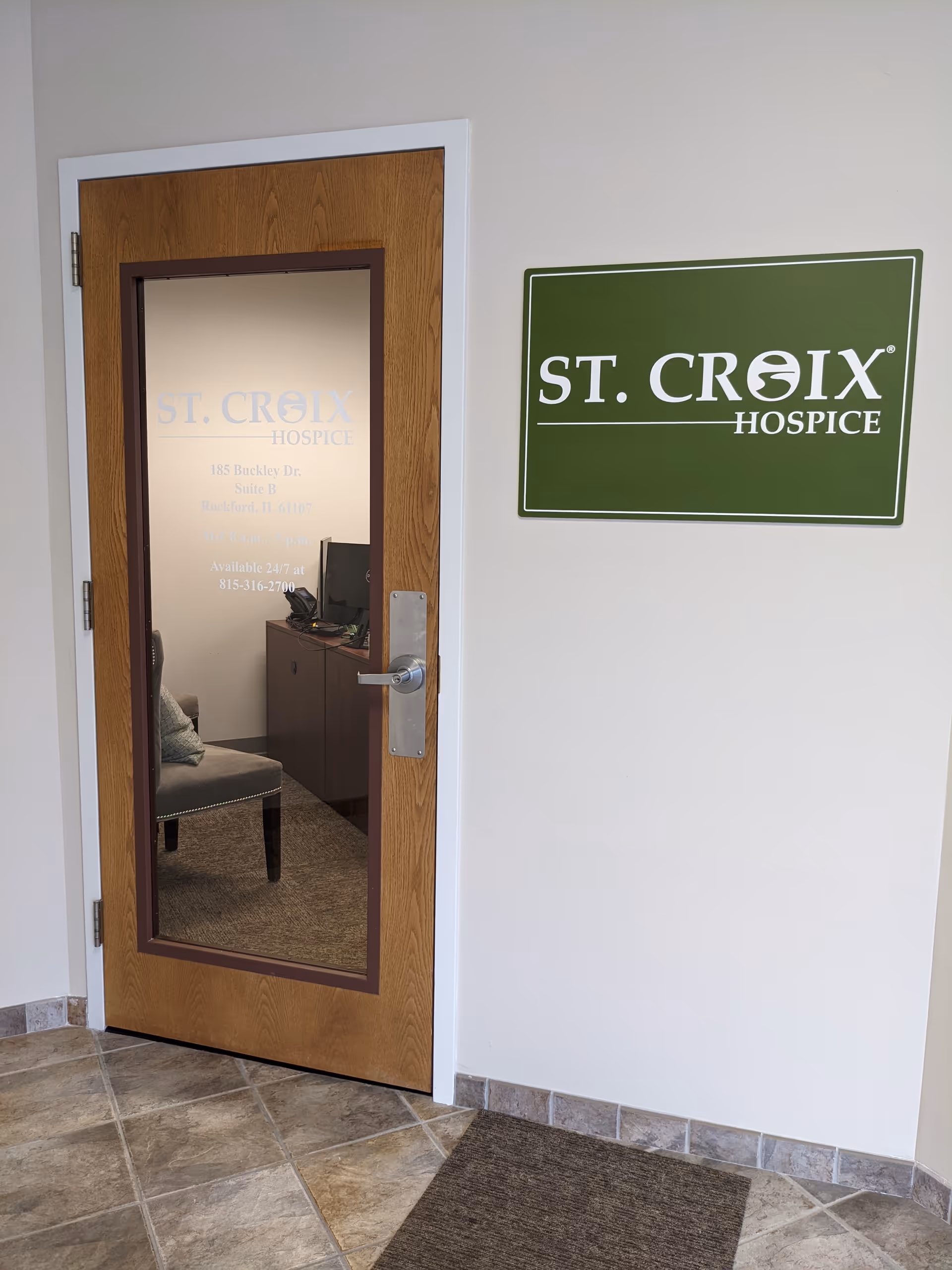 Interior doorway with St. Croix Hospice sign on the wall beside a wooden-framed glass door.
