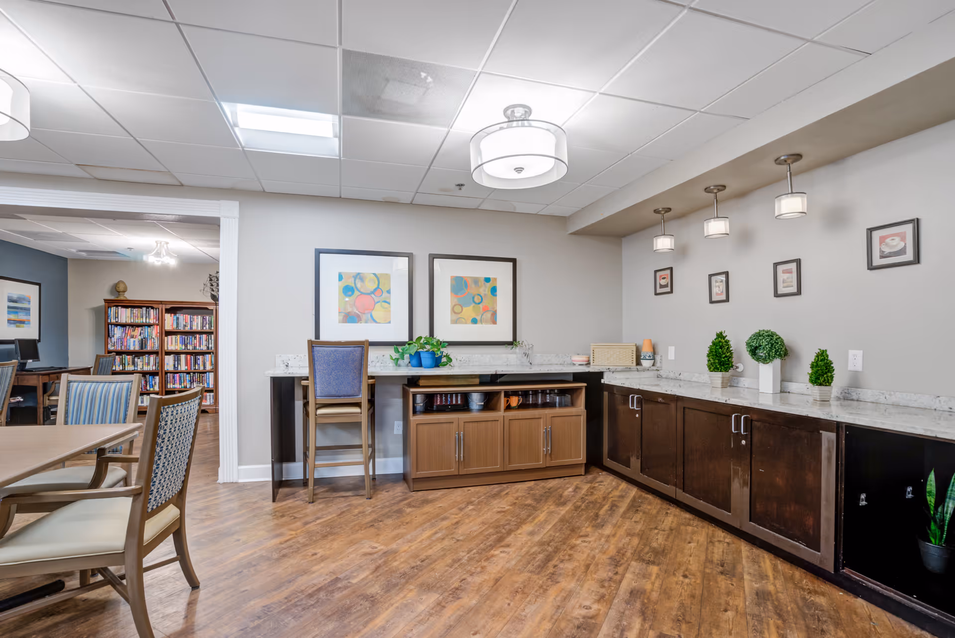 Spacious senior living facility common area with a long counter, cabinets, seating, and art.