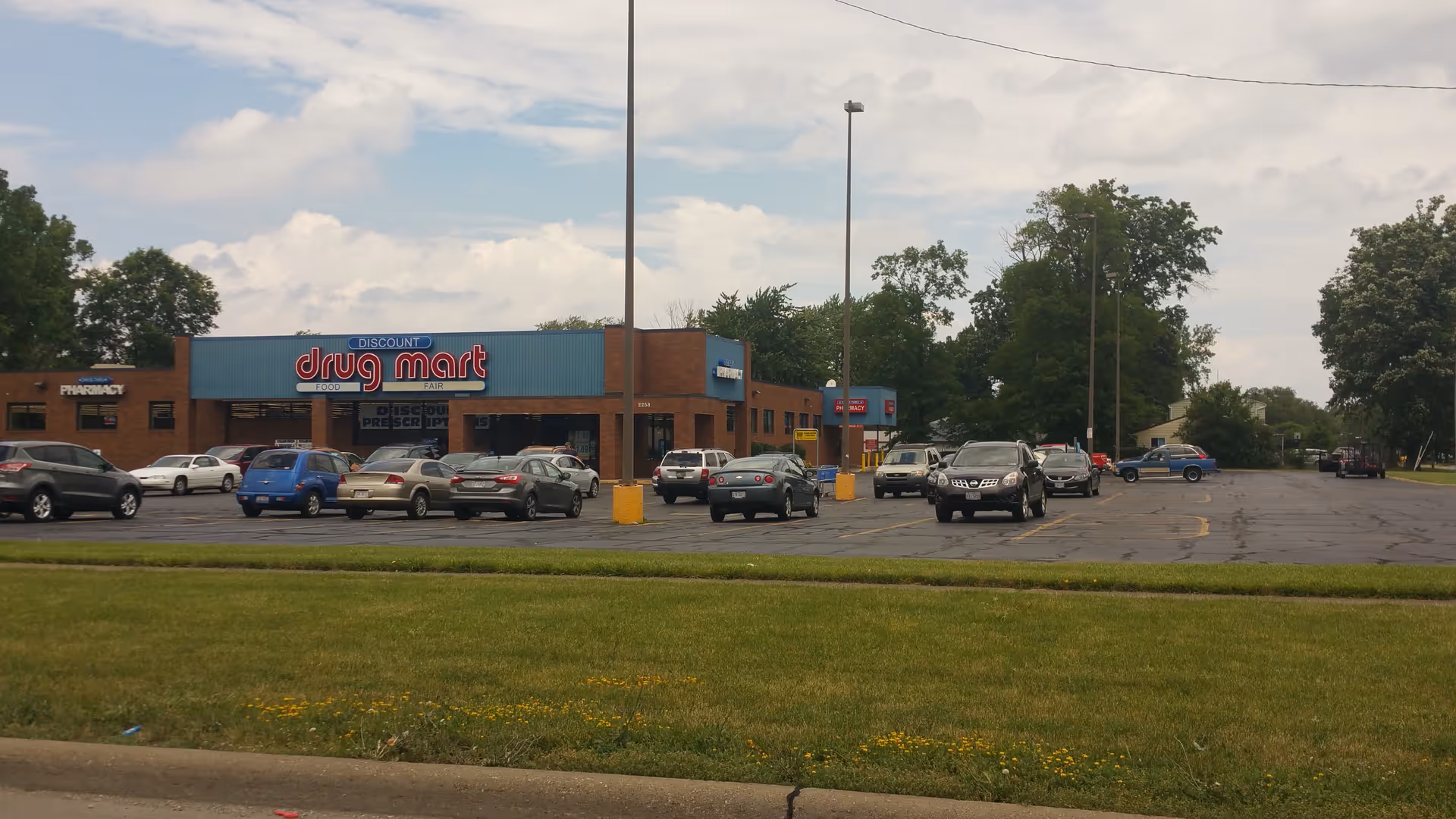 Discount Drug Mart storefront with parking lot and trees in the distance.