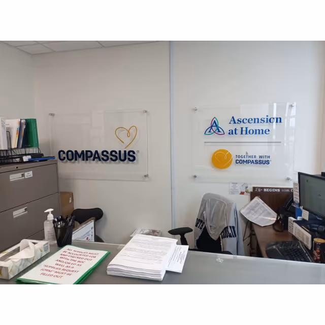 Reception area inside a Compassus facility with signs and office desk items