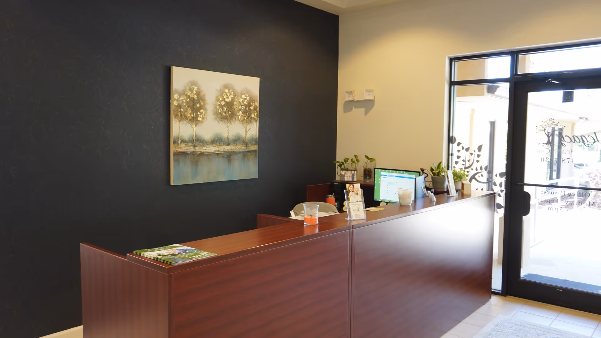 Reception desk in a modern facility lobby with a glass entrance door.
