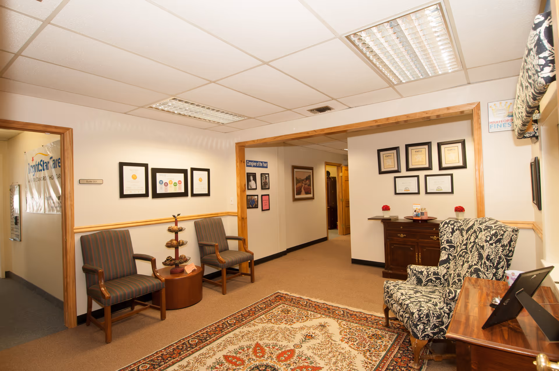 BrightStar Care lobby with chairs, a rug, framed certificates, and a wooden cabinet.
