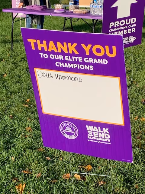 Purple 'Thank You' sign on grass at outdoor Walk to End Alzheimer's event.